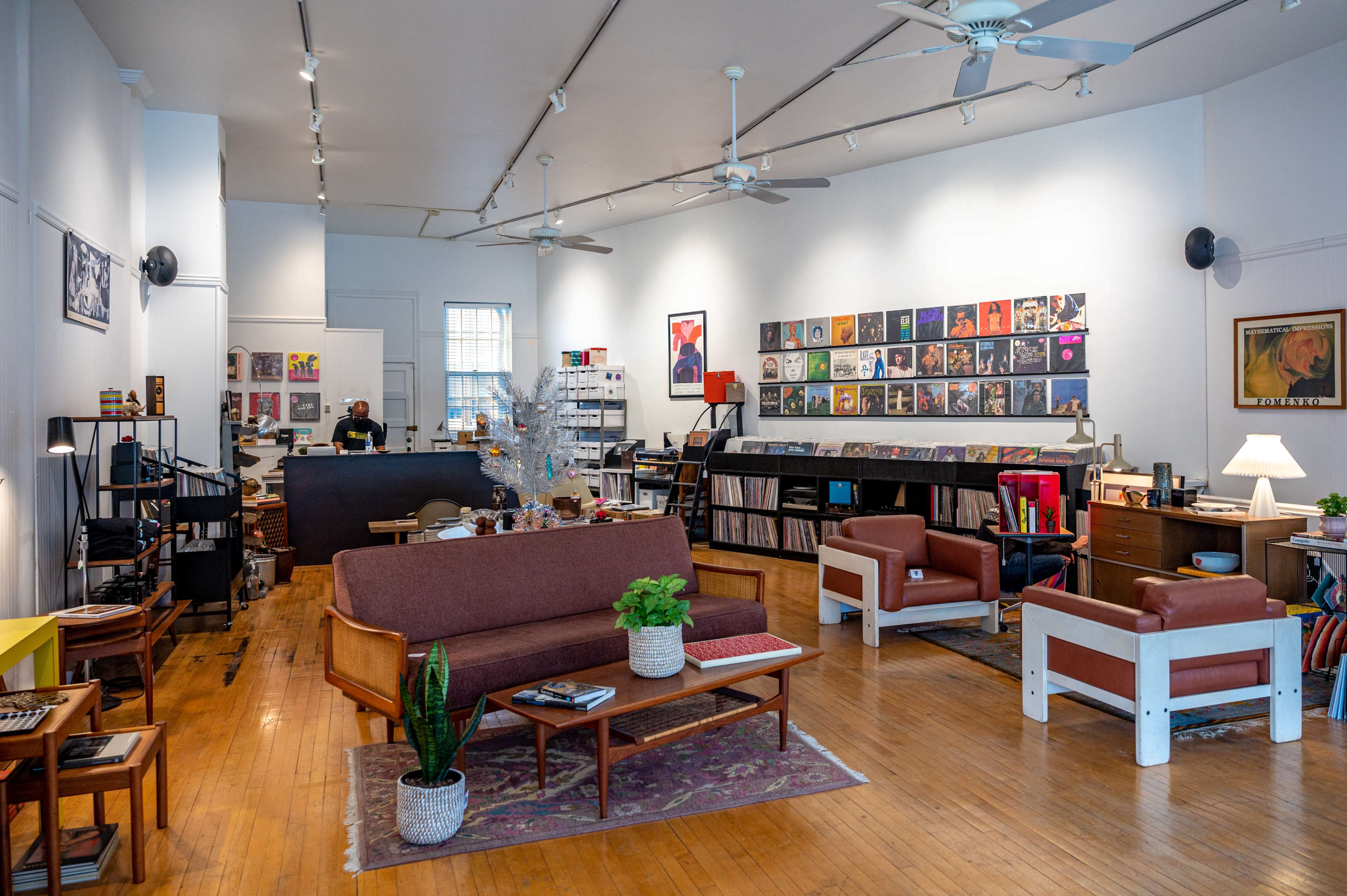 A spacious record store with shelves of vinyl records, seating areas, and a service counter in the background.