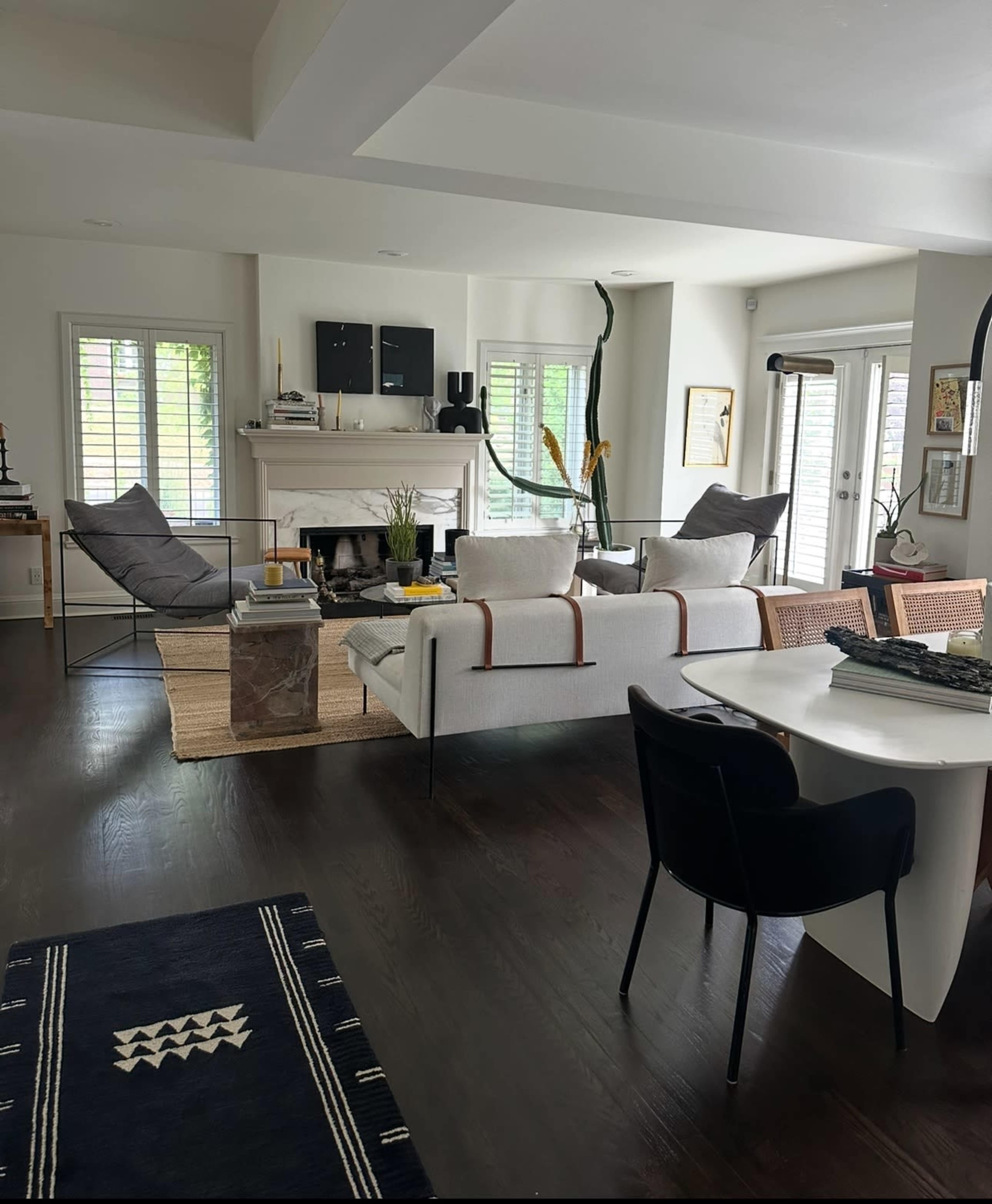 The image shows a modern living room with a white sofa, a fireplace, and various seating options, all arranged in an open layout.