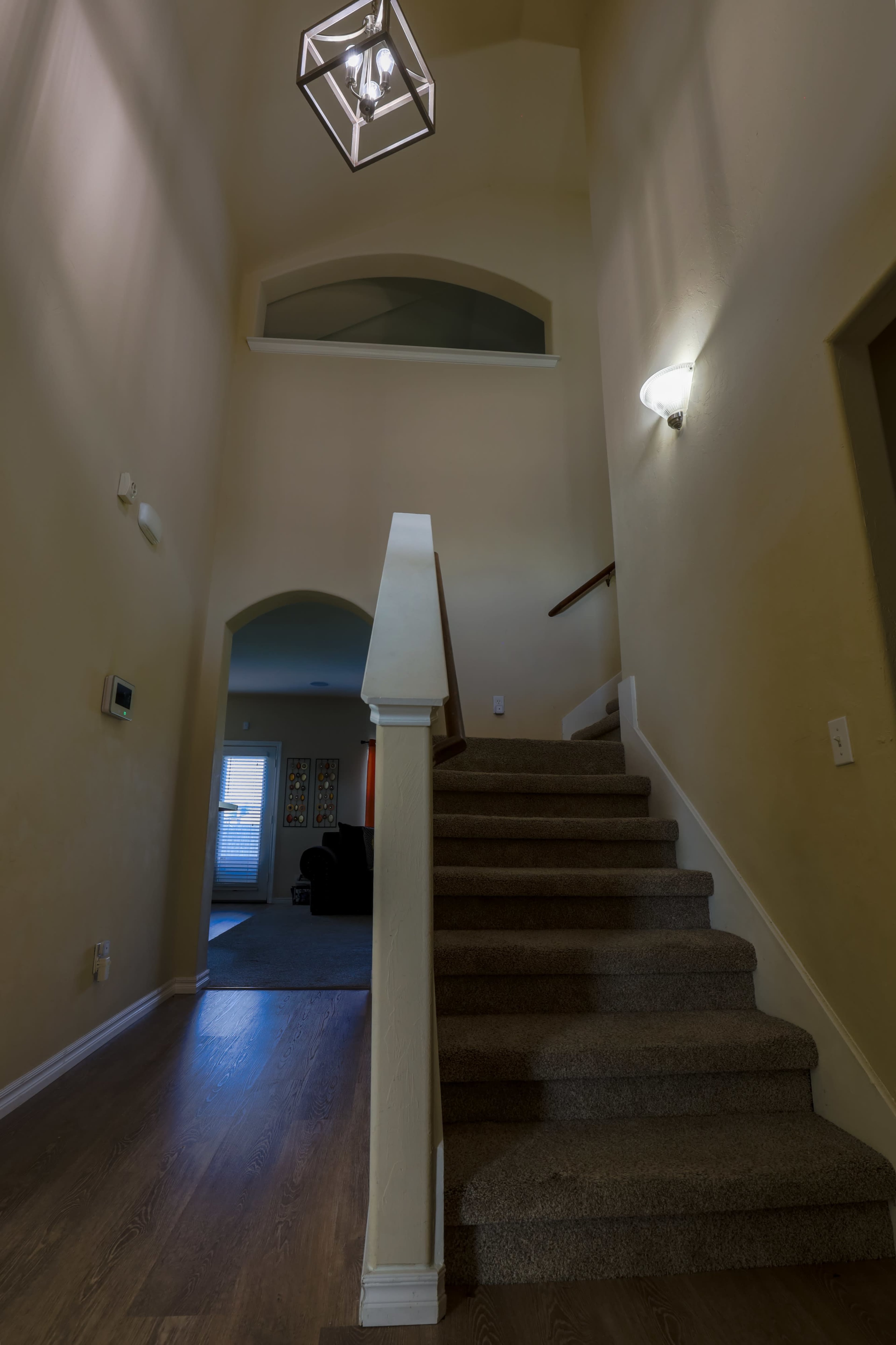 A staircase leading to a second floor, with a hanging light fixture and walls painted in a neutral color.
