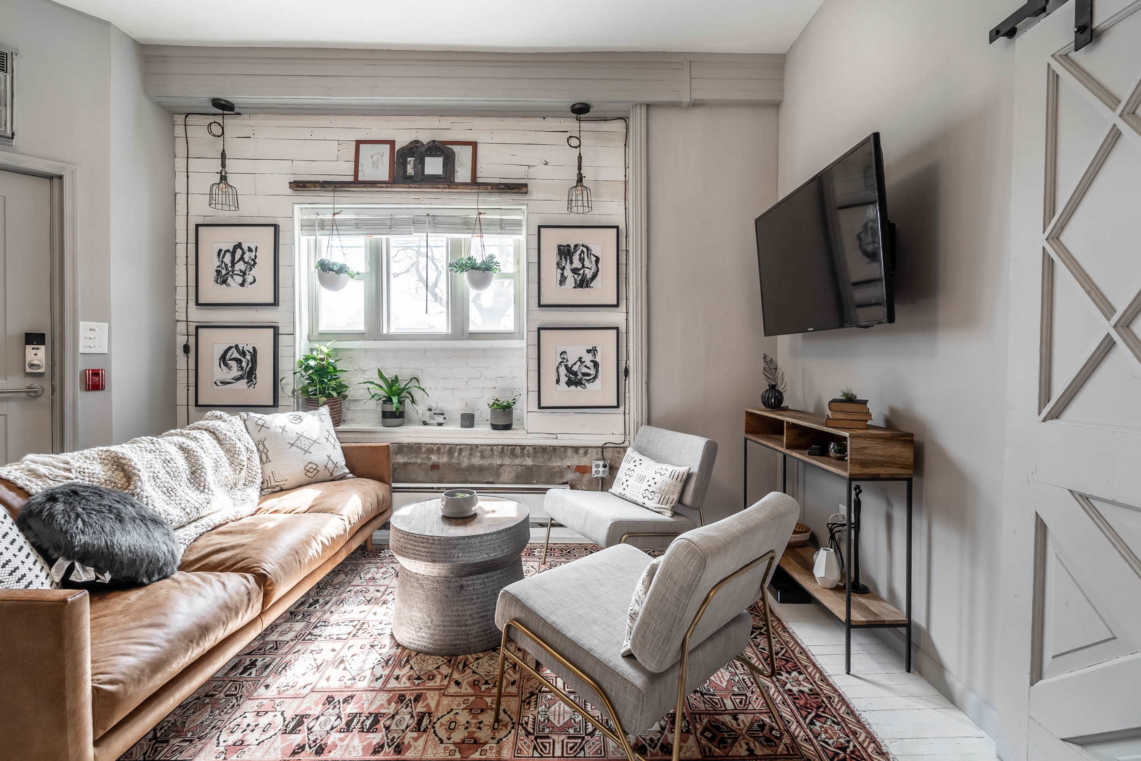 A modern living room with a leather sofa, a round table, and framed artwork on the walls.