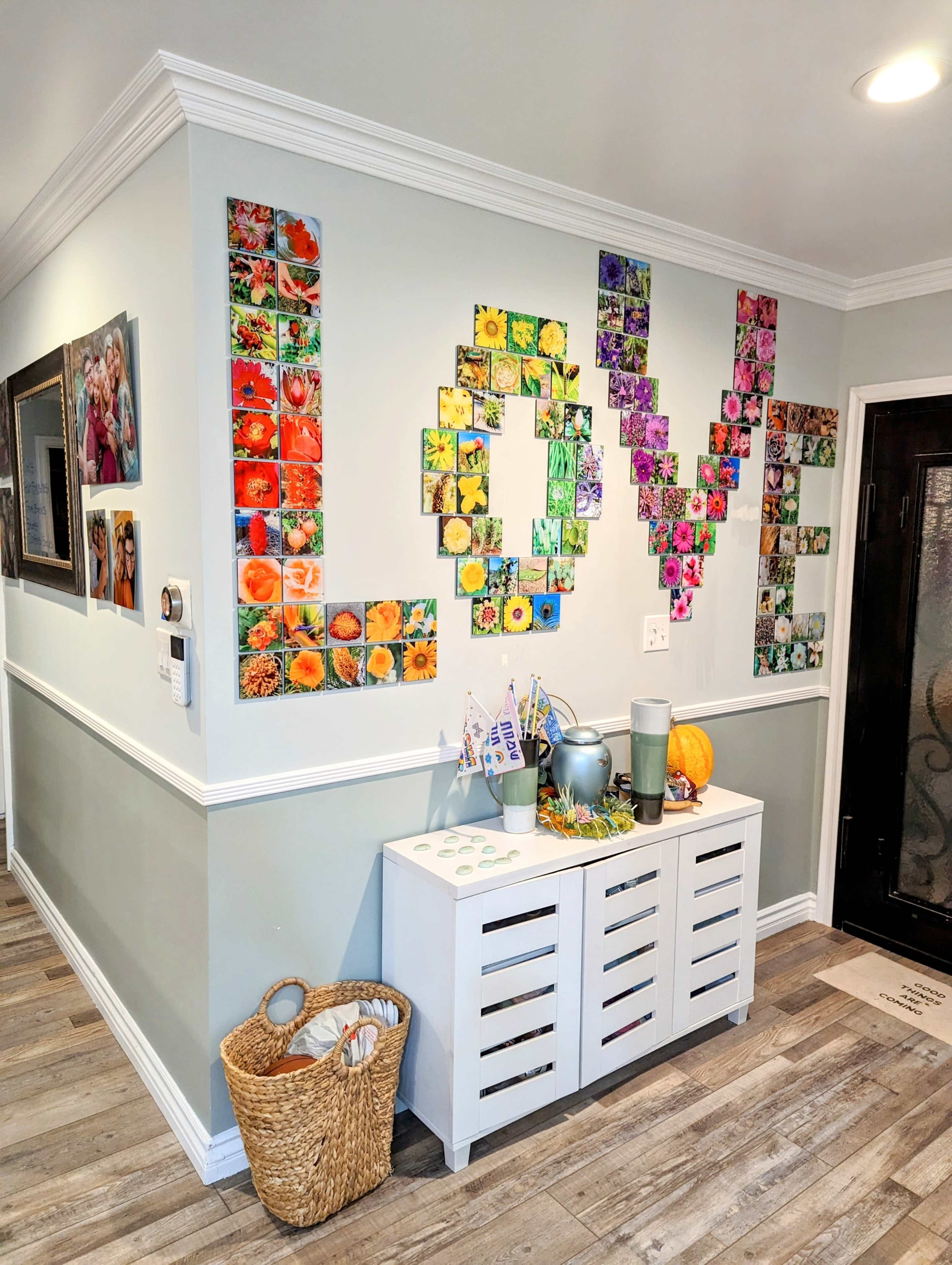 The image shows a wall decorated with colorful photographs arranged to spell the word "LOVE," above a white storage cabinet with various items on top.
