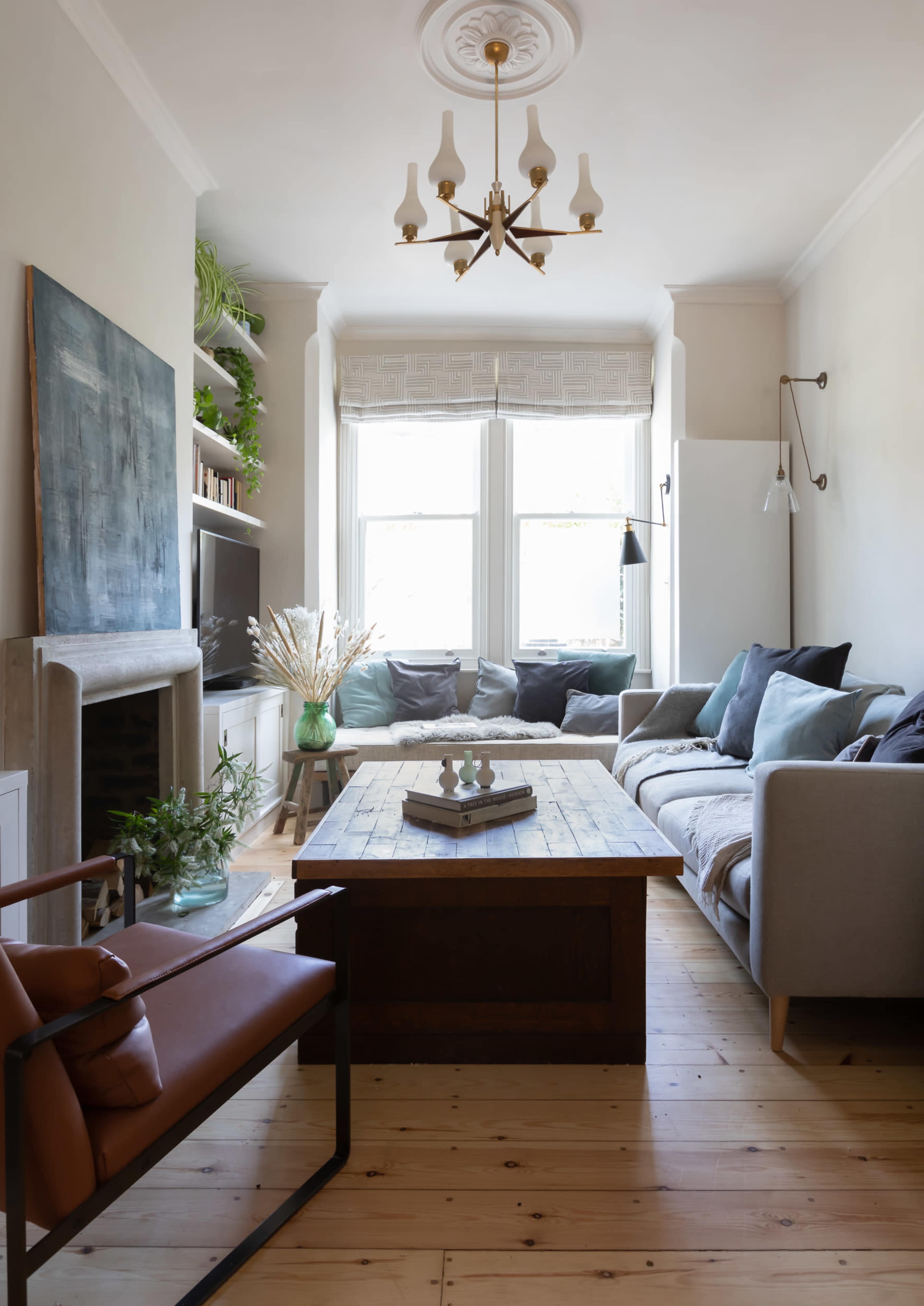The living room features a wooden coffee table surrounded by a mix of sofas and armchairs, with large windows allowing natural light to fill the space.