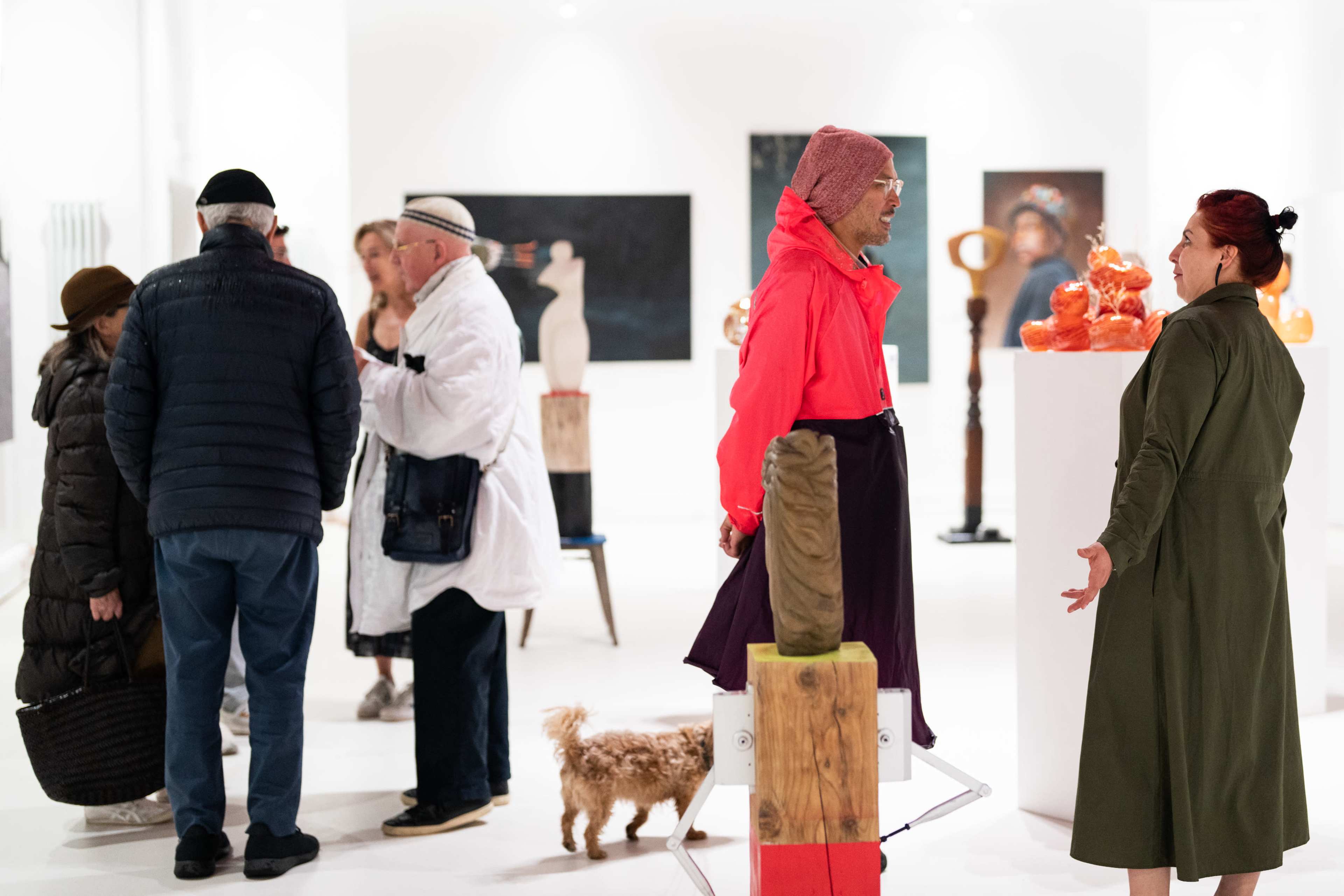 A group of people are interacting in an art gallery featuring various sculptures and artworks on display.