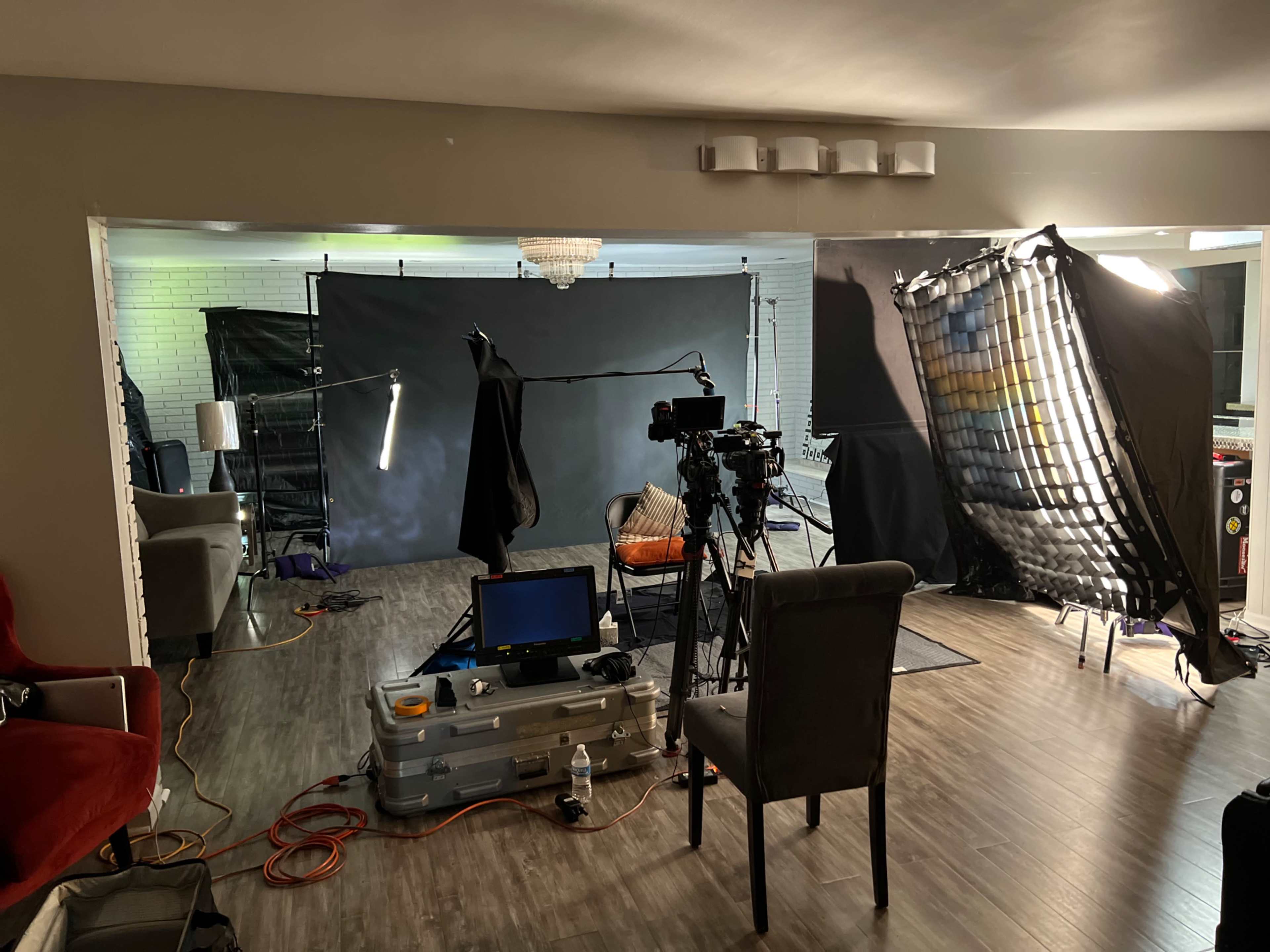 A film setup showcases a camera, lighting equipment, and a backdrop in a spacious living area.