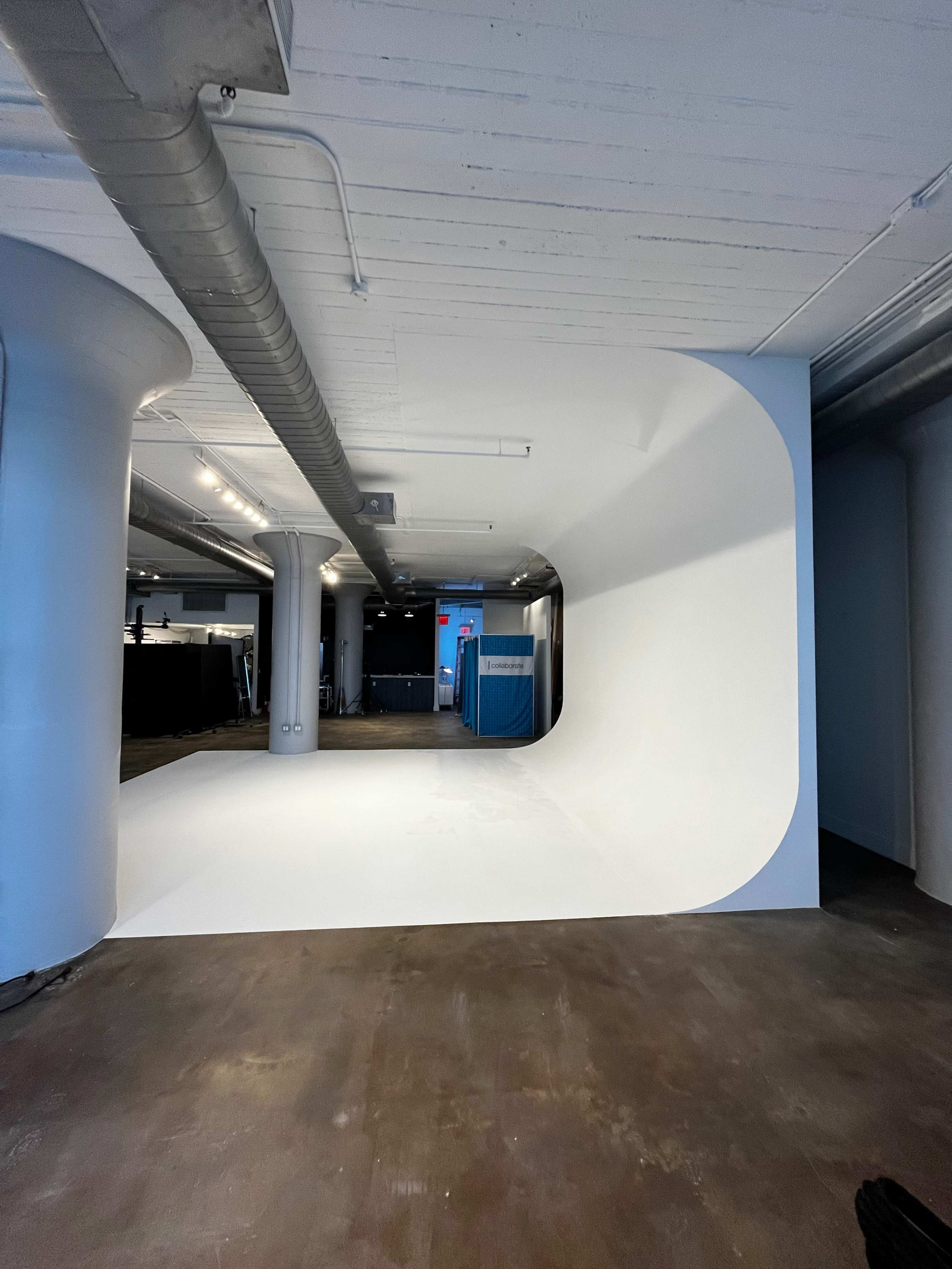 A spacious interior with a curved white backdrop against a concrete floor.