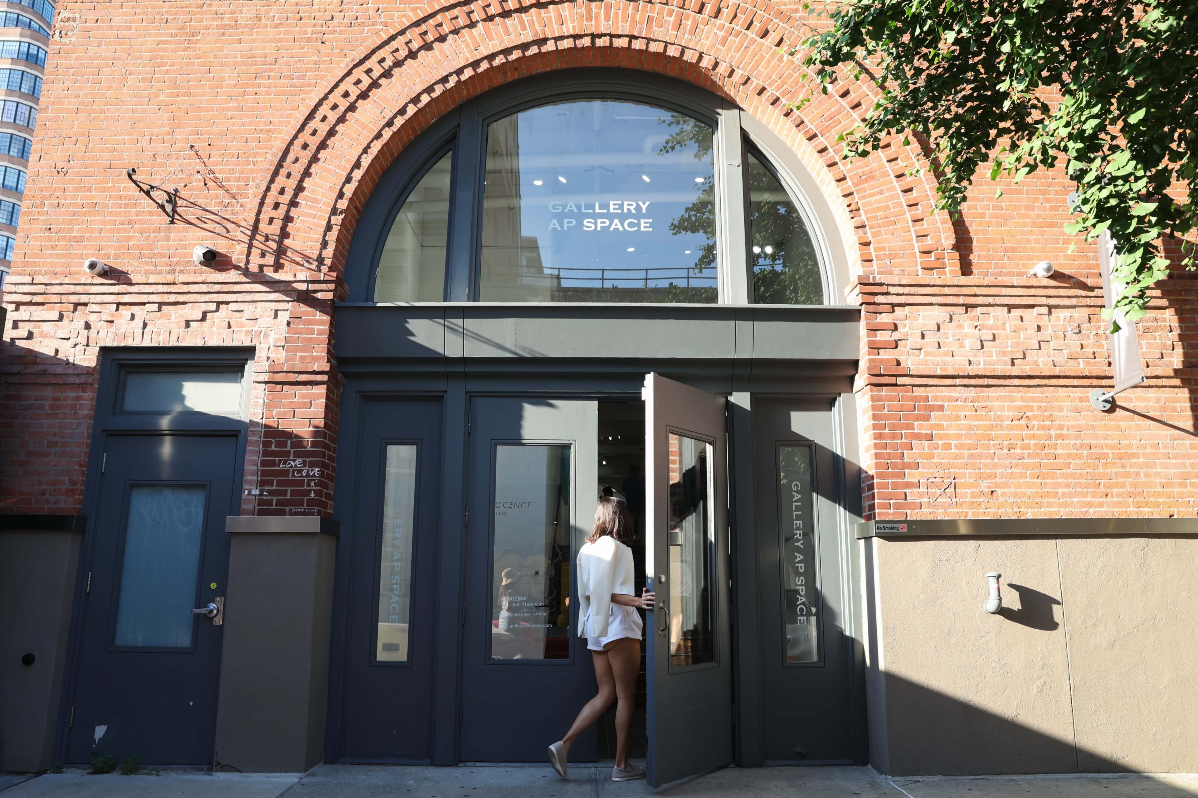 A person is entering a building with a large archway and the words "GALLERY AP SPACE" displayed above the doorway.