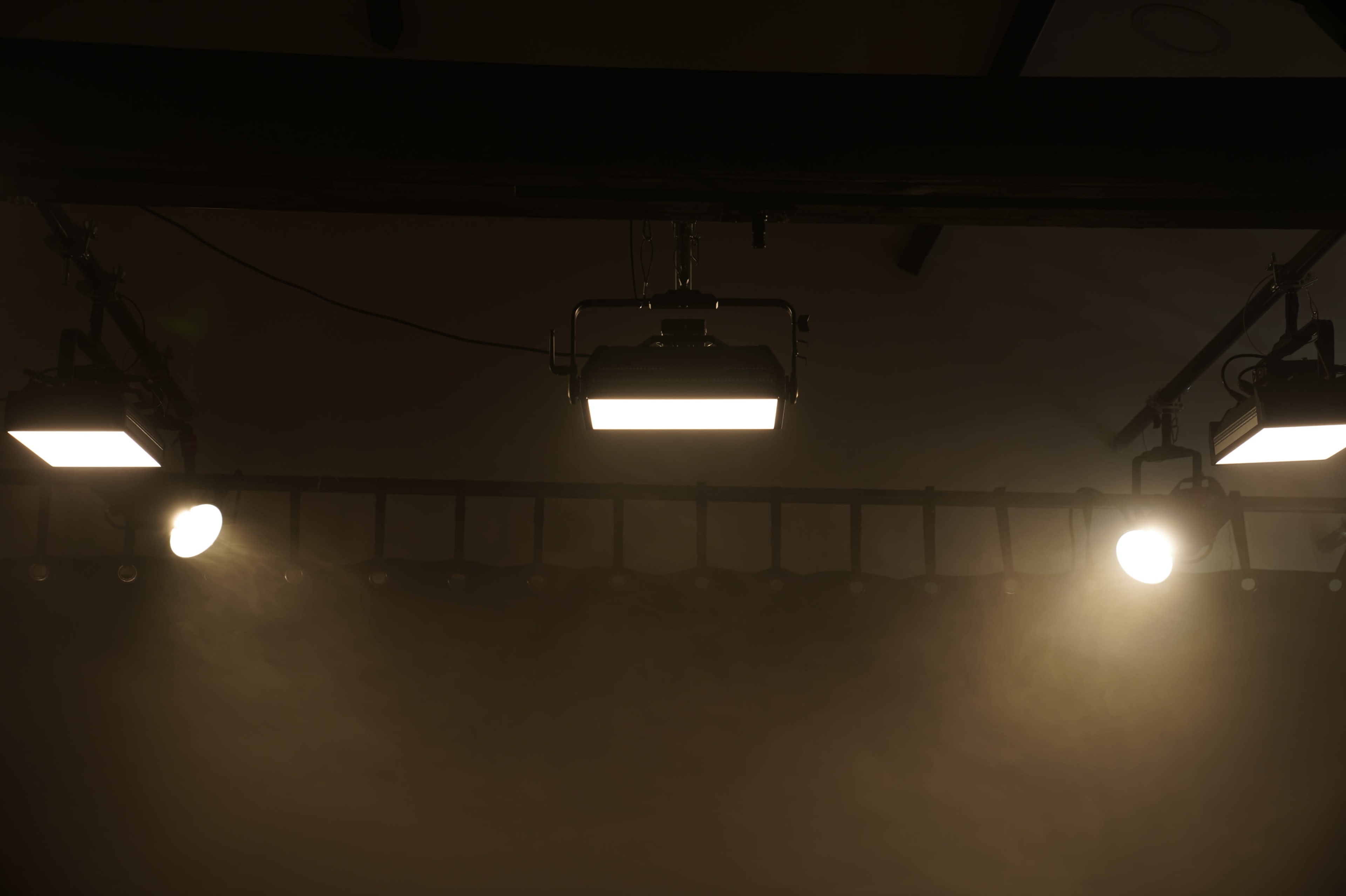 Three overhead stage lights positioned above a misty scene.