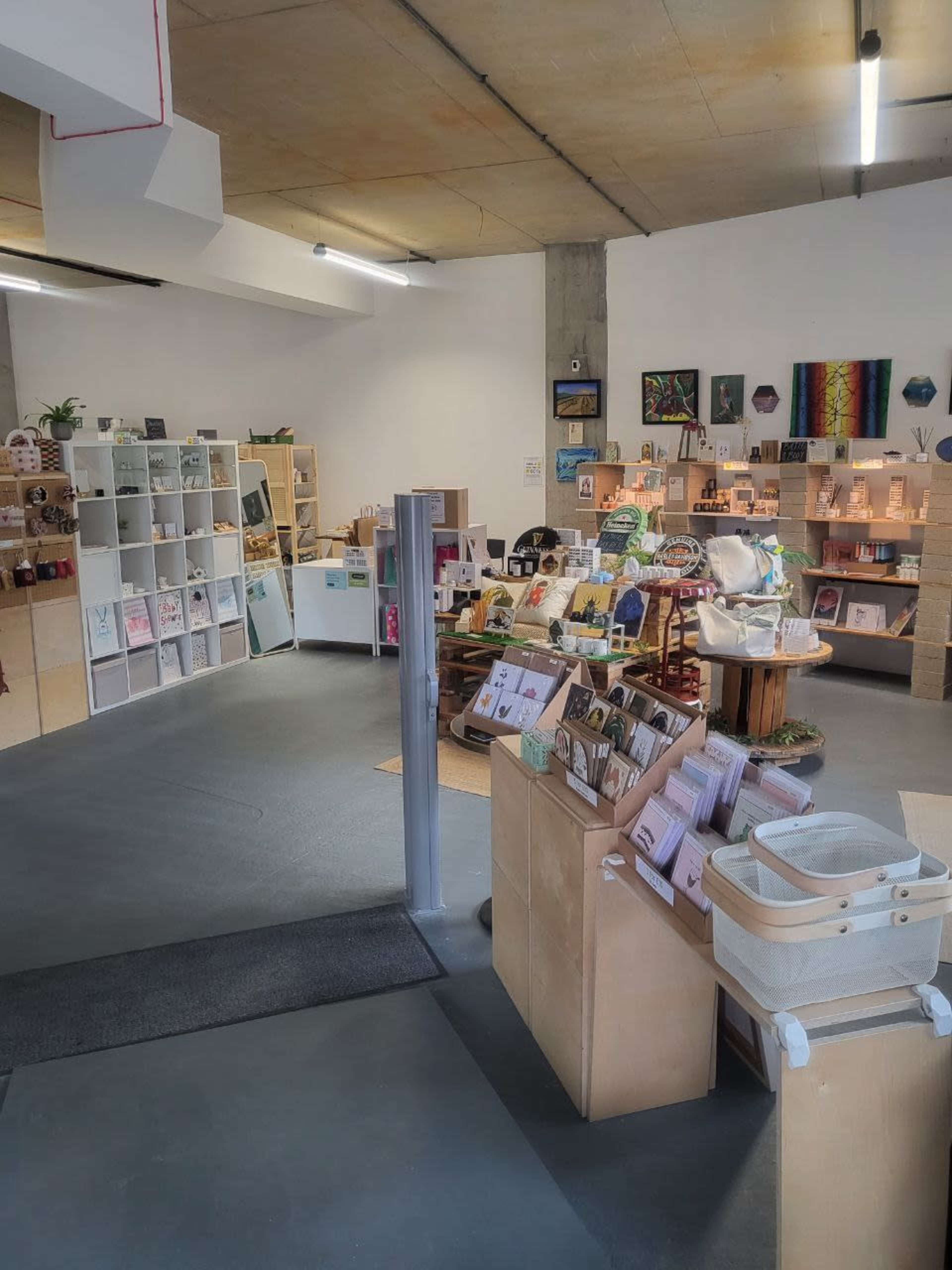A well-organized retail space featuring wooden shelves and displays filled with various products, including cards, art, and decor items.