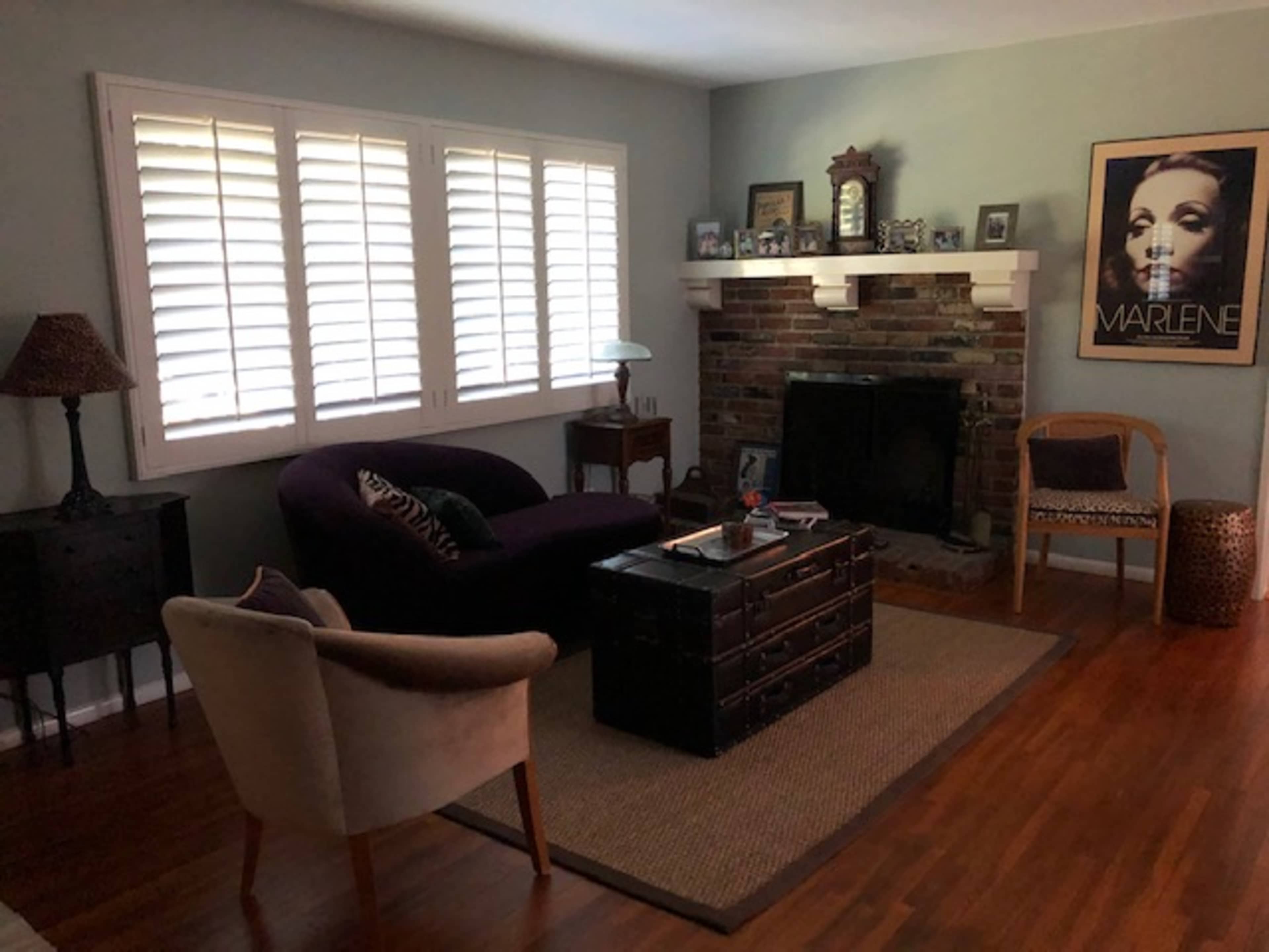 The living room features a purple sofa, a wooden coffee table, and a fireplace with a brick surround, complemented by a framed poster on the wall.