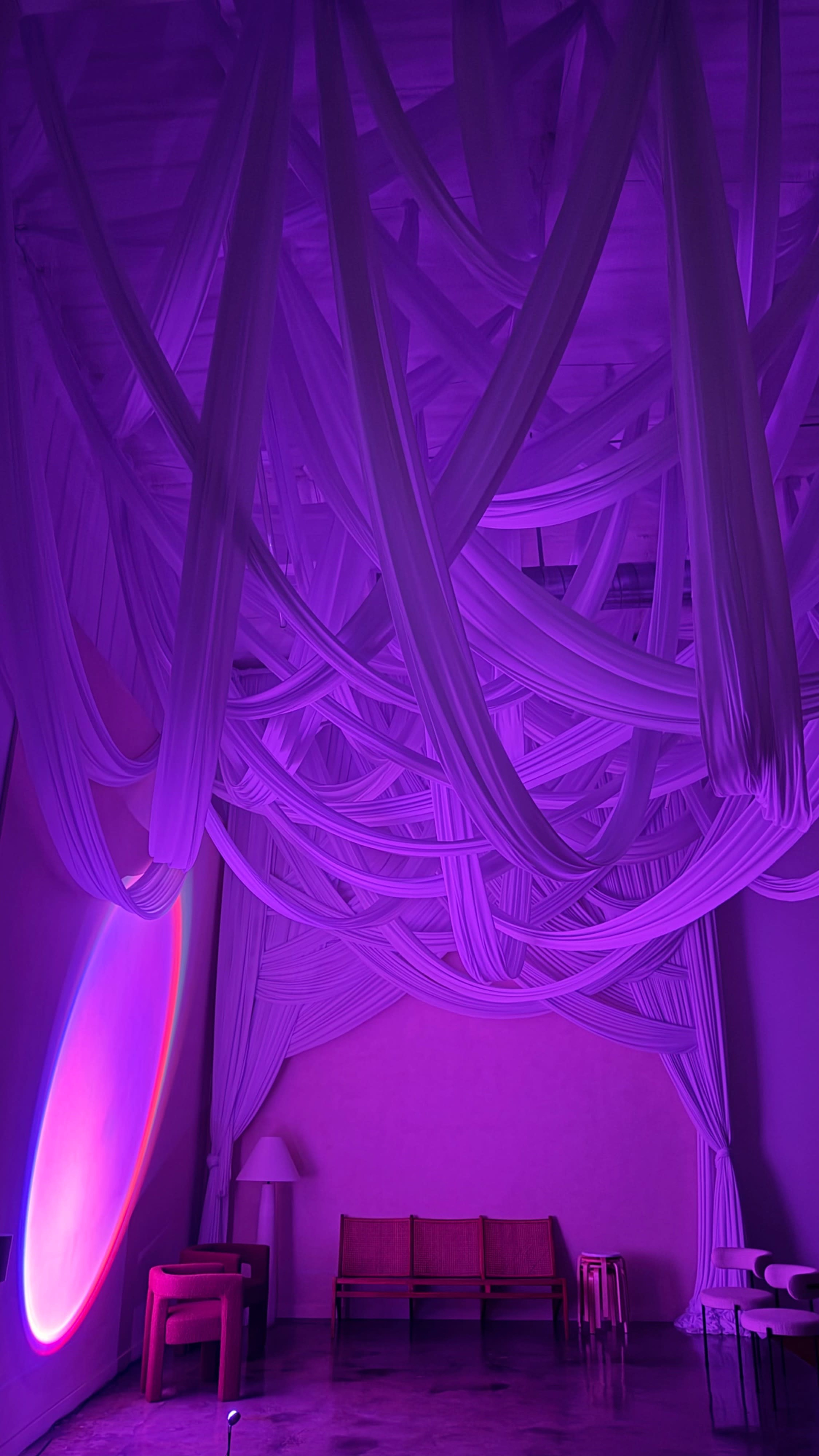 The image features a room with purple lighting and draped fabric hanging from the ceiling, creating an intricate overhead design.