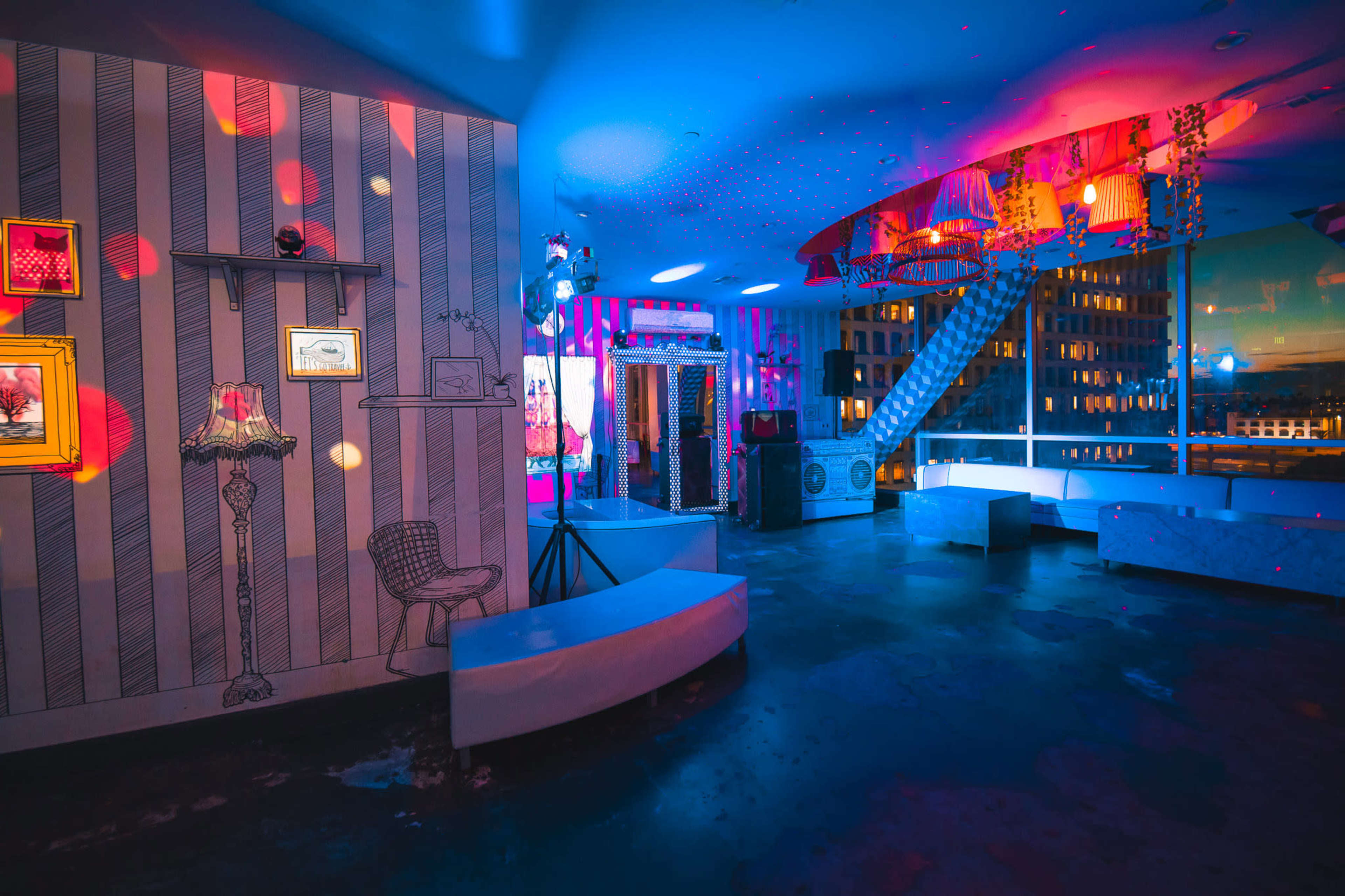 The image shows a brightly lit lounge with patterned walls, modern furniture, and ambient lighting effects.