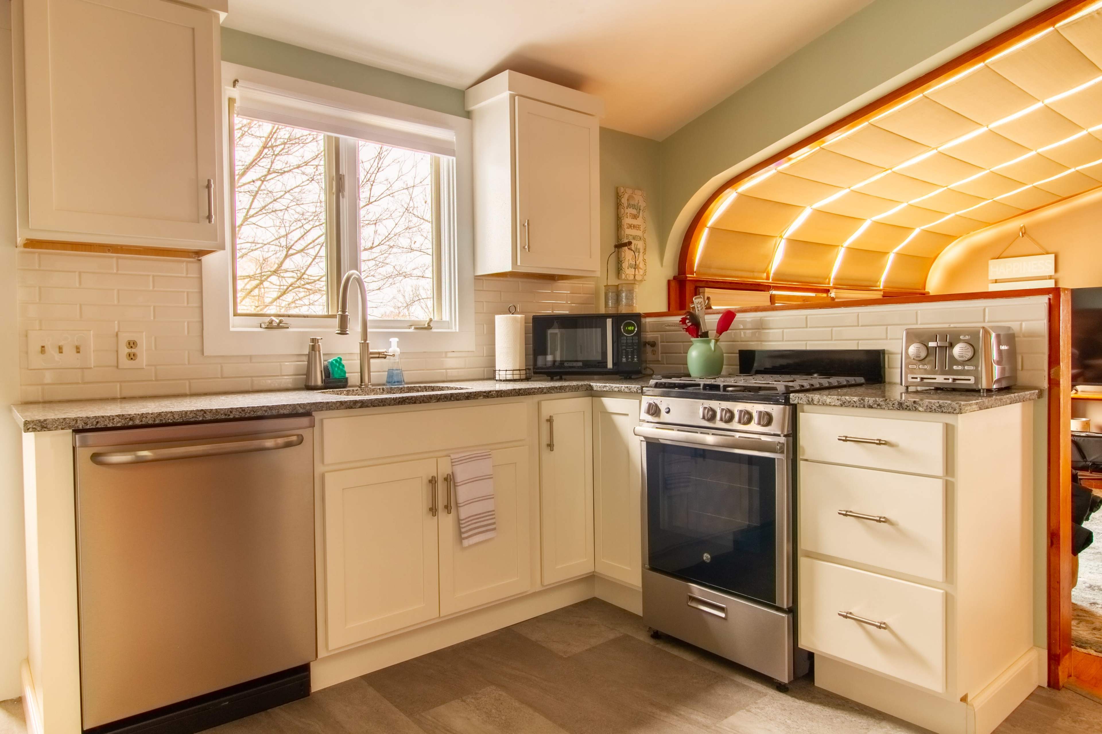 A modern kitchen with white cabinetry, a stainless steel oven, and a window above the sink.