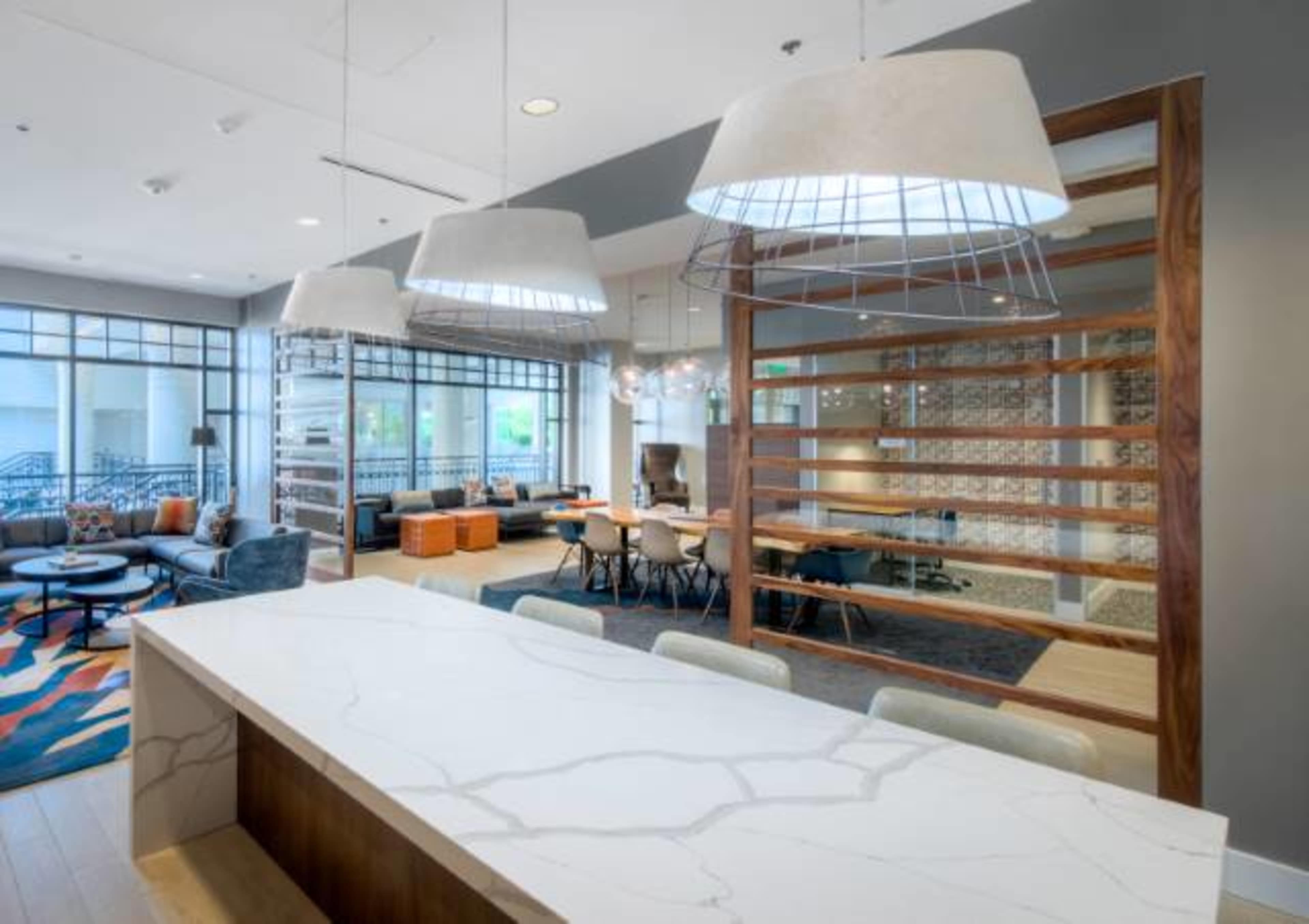 A modern communal lounge area with a large countertop, pendant lighting, and various seating arrangements.