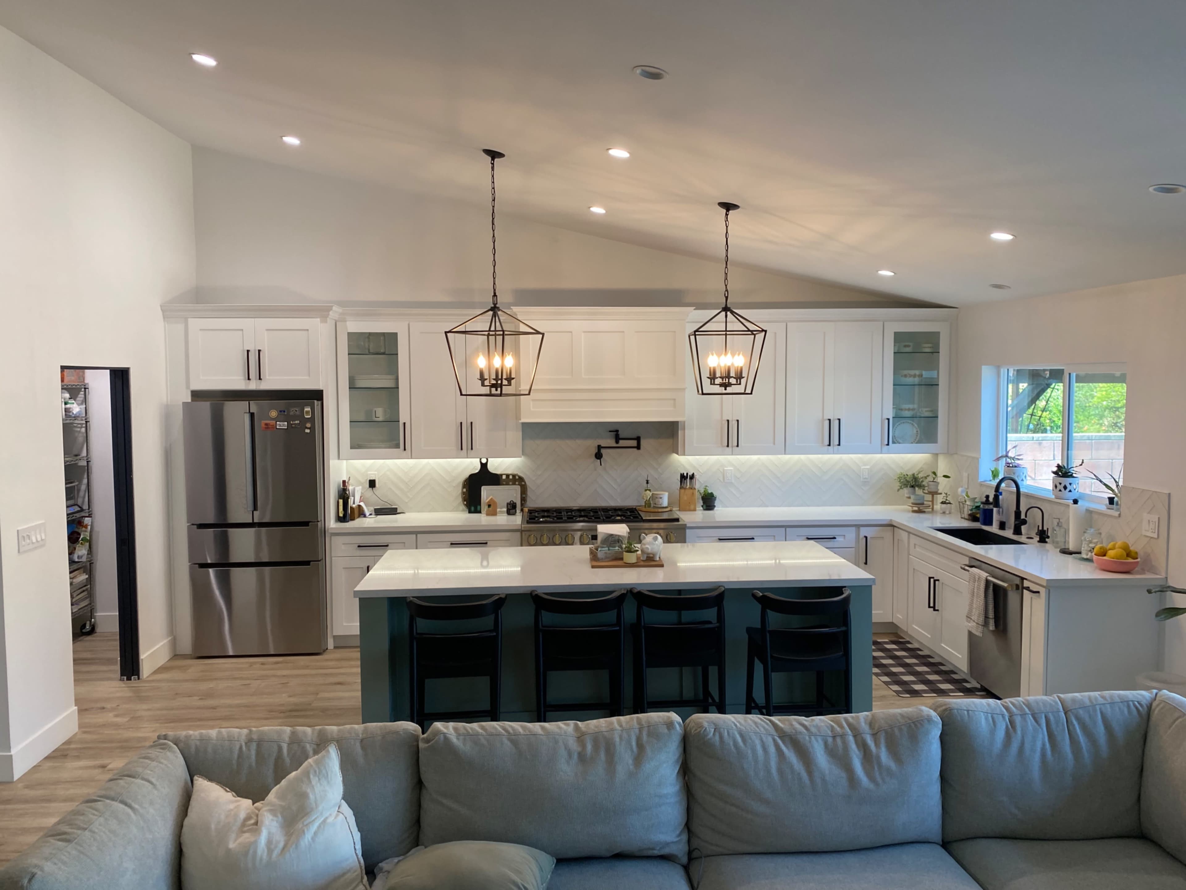 A modern kitchen with white cabinetry, a large island with seating, and two pendant lights hanging above.