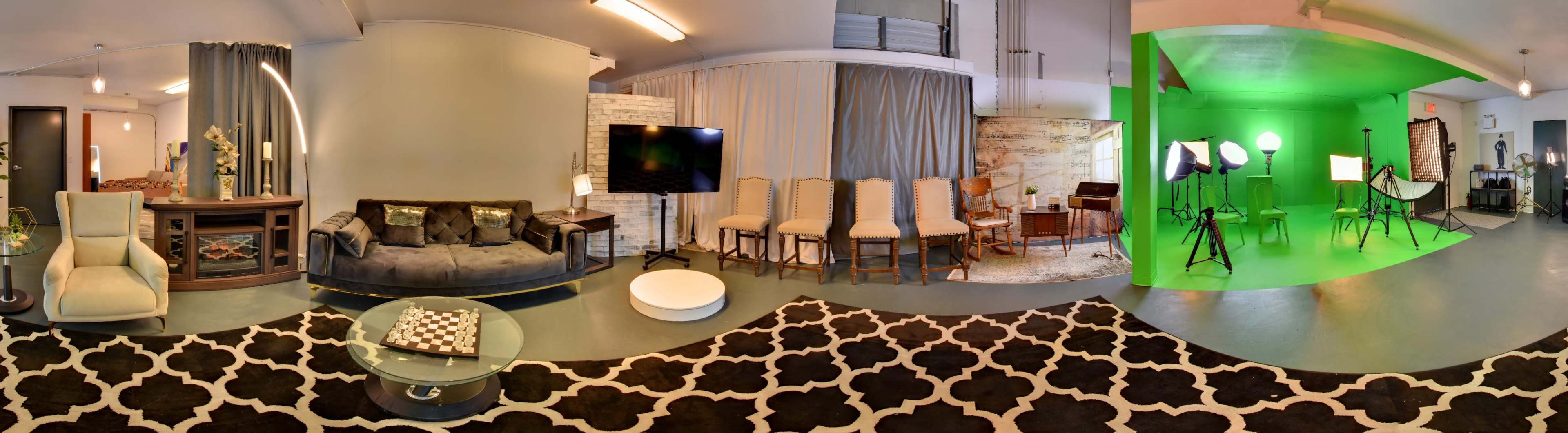 The image shows a spacious room divided into two areas: one features a cozy seating arrangement with decorative elements, and the other is a green screen setup with multiple lights and equipment.
