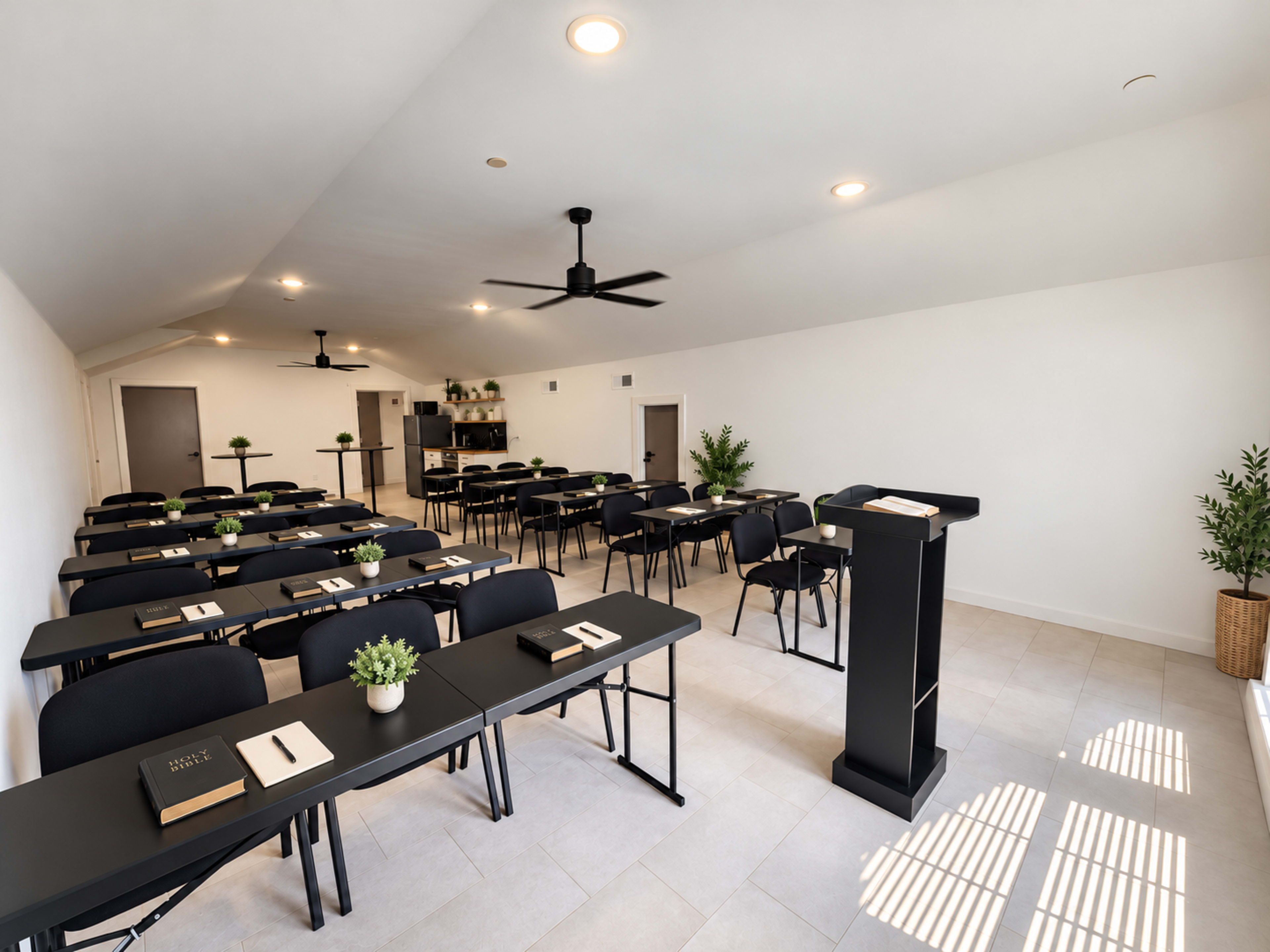 The image shows a modern classroom or meeting space arranged with rows of tables and chairs, featuring a podium at the front and potted plants in the corners.