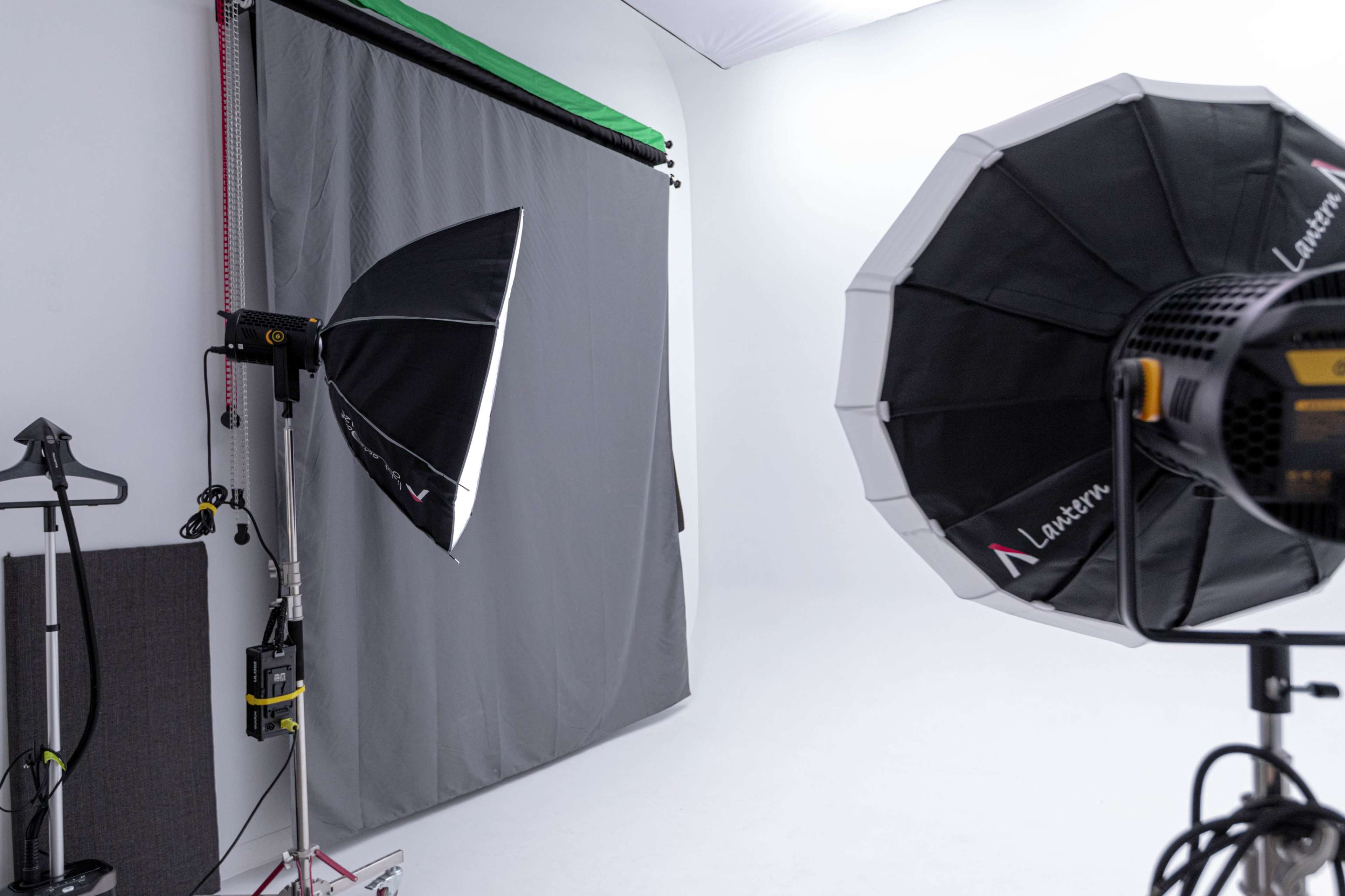 The image shows a photography studio setup featuring a gray backdrop and two softbox lights.