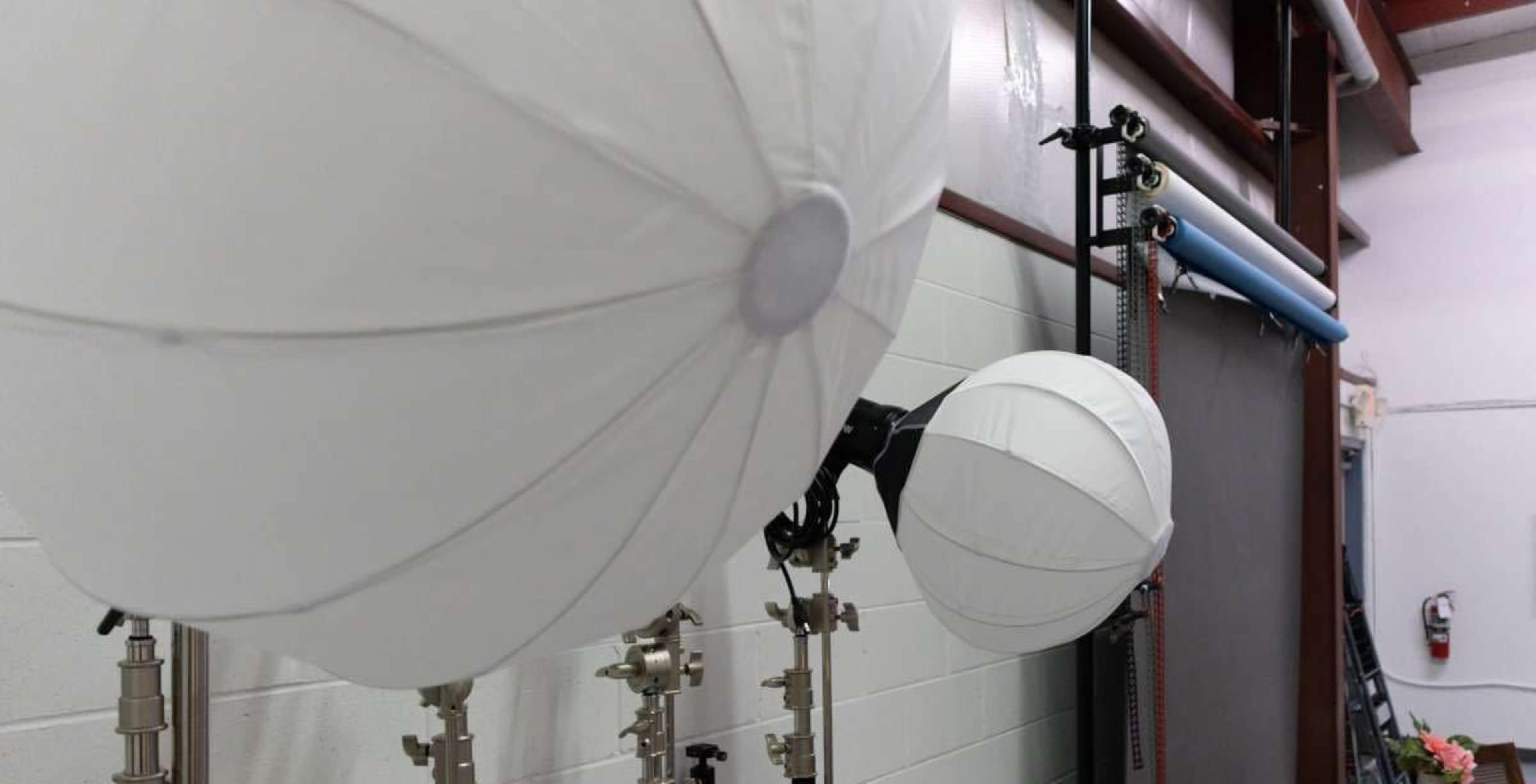 The image shows several large white balloons attached to metal stands in a workshop or studio environment.