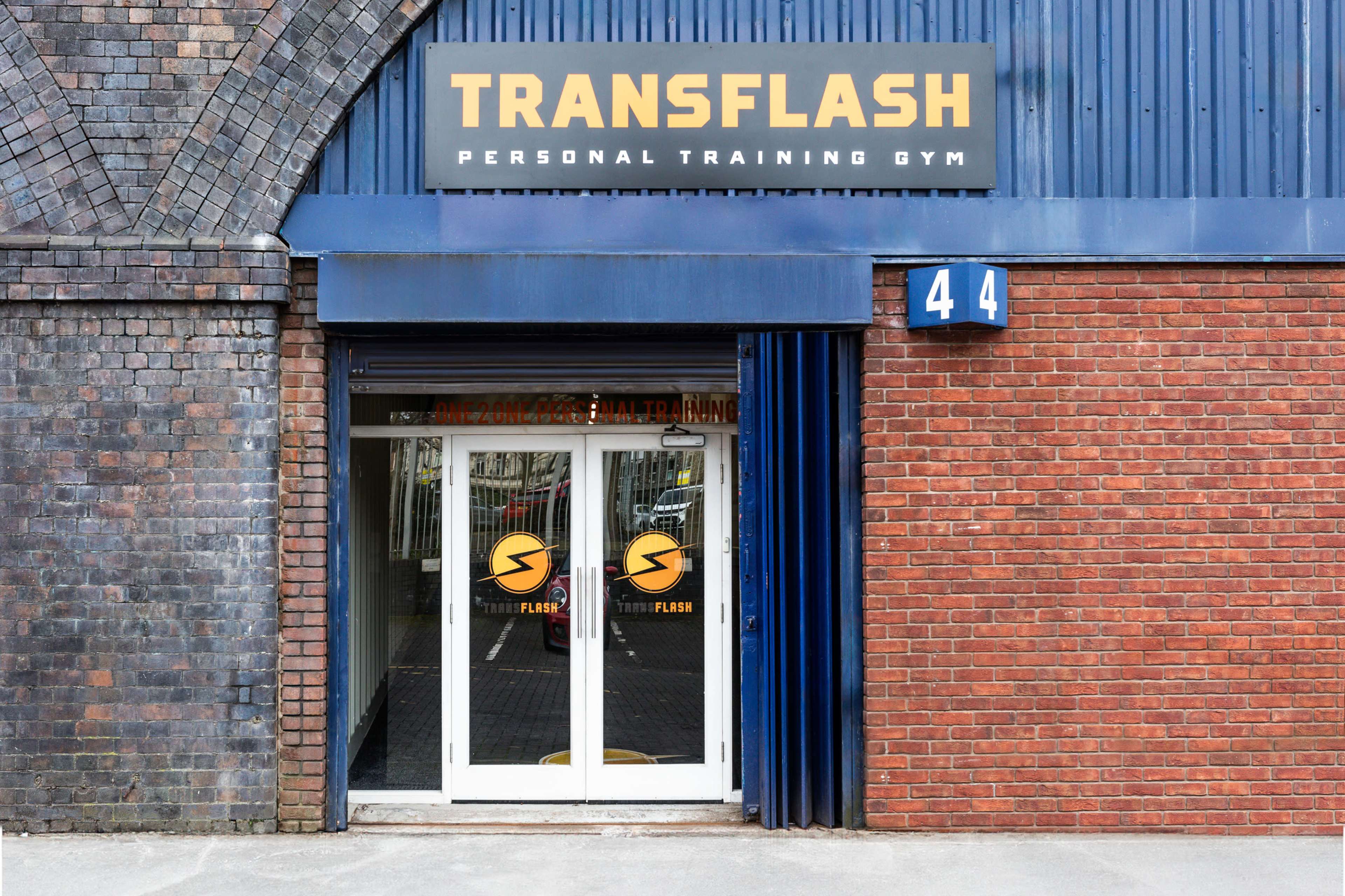 The image shows the entrance of a personal training gym named "Transflash," featuring a modern design with glass doors and bold signage.