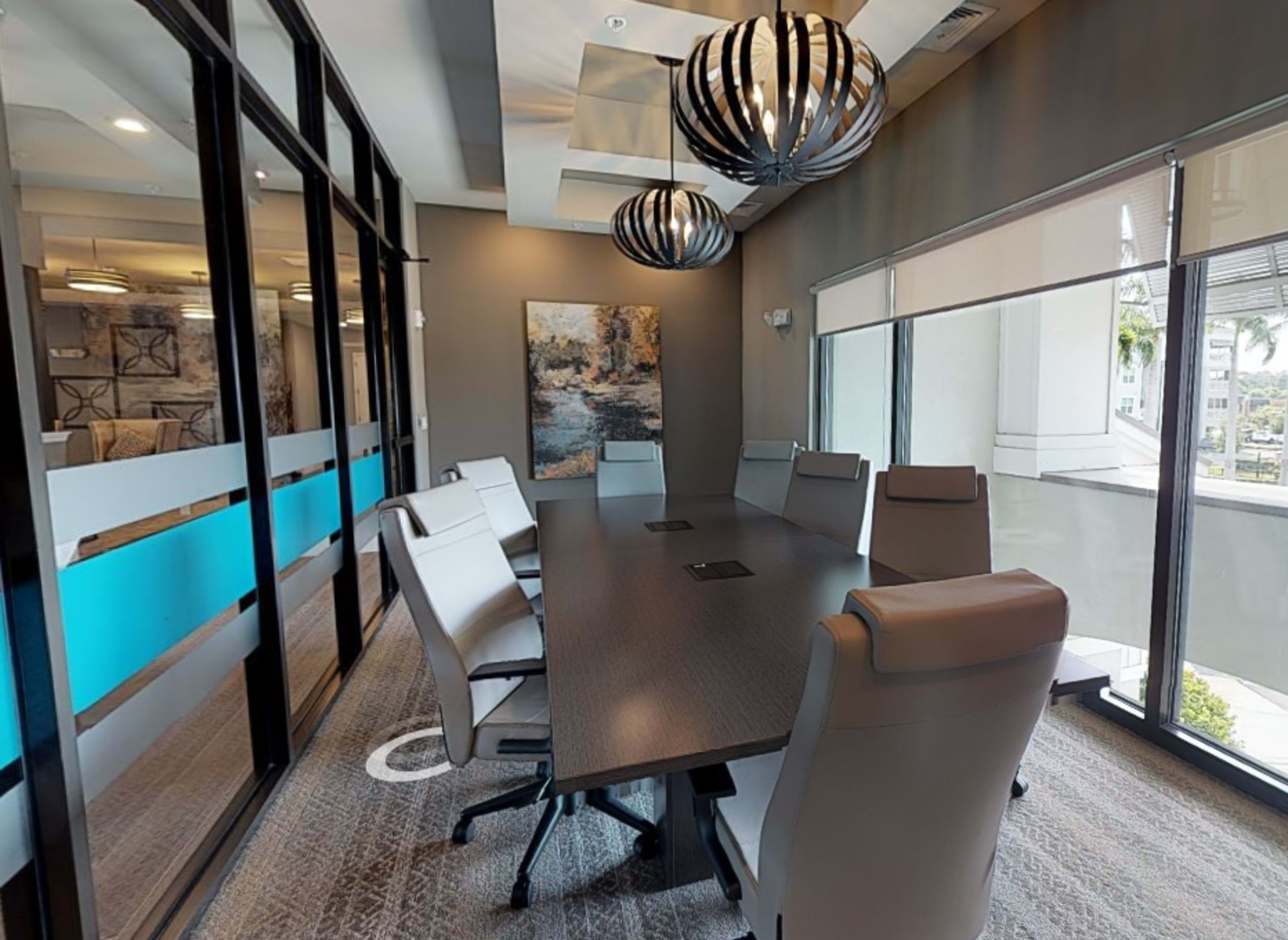 A modern conference room with a long table, ergonomic chairs, and distinctive pendant lights overhead.