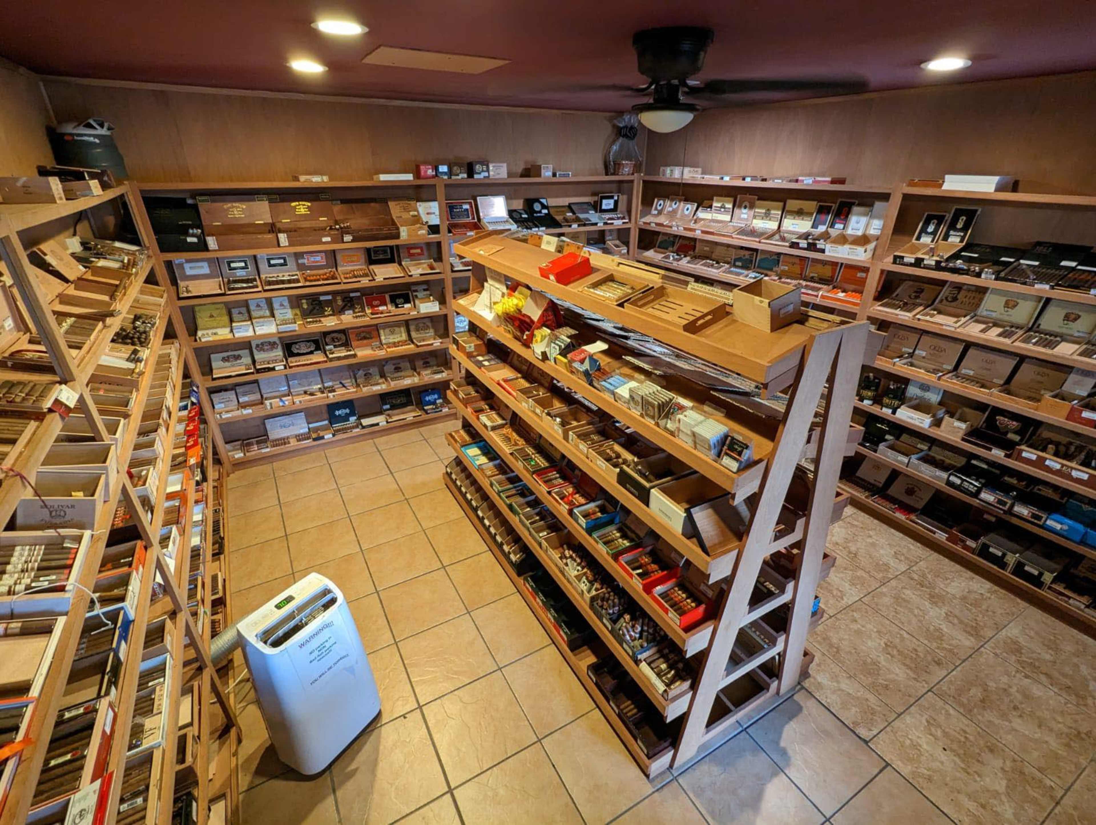 A well-organized cigar store with wooden shelves displaying a variety of cigar boxes in a tiled room.
