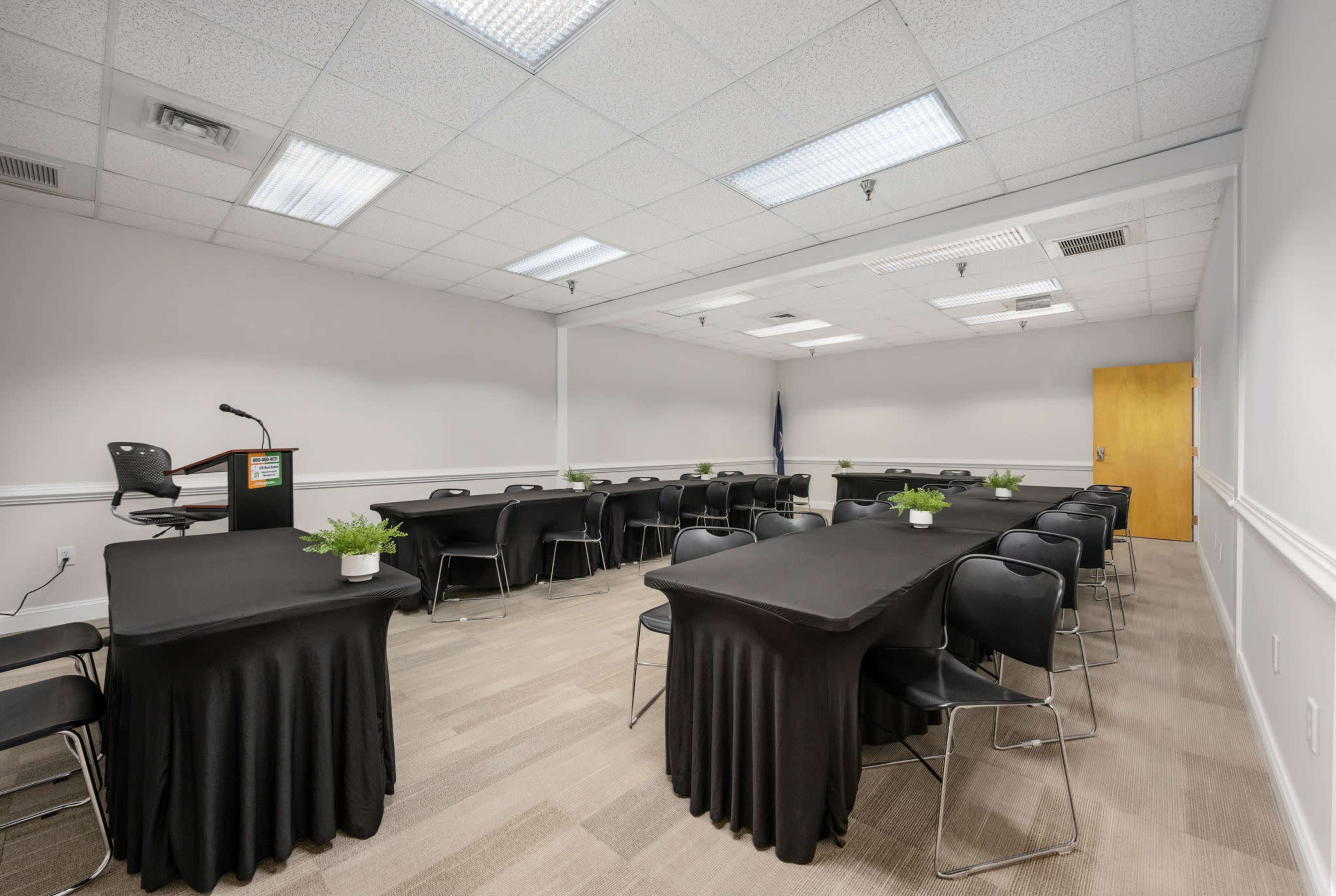 A conference room set up with multiple rows of black tablecloth-covered tables and chairs arranged around them.