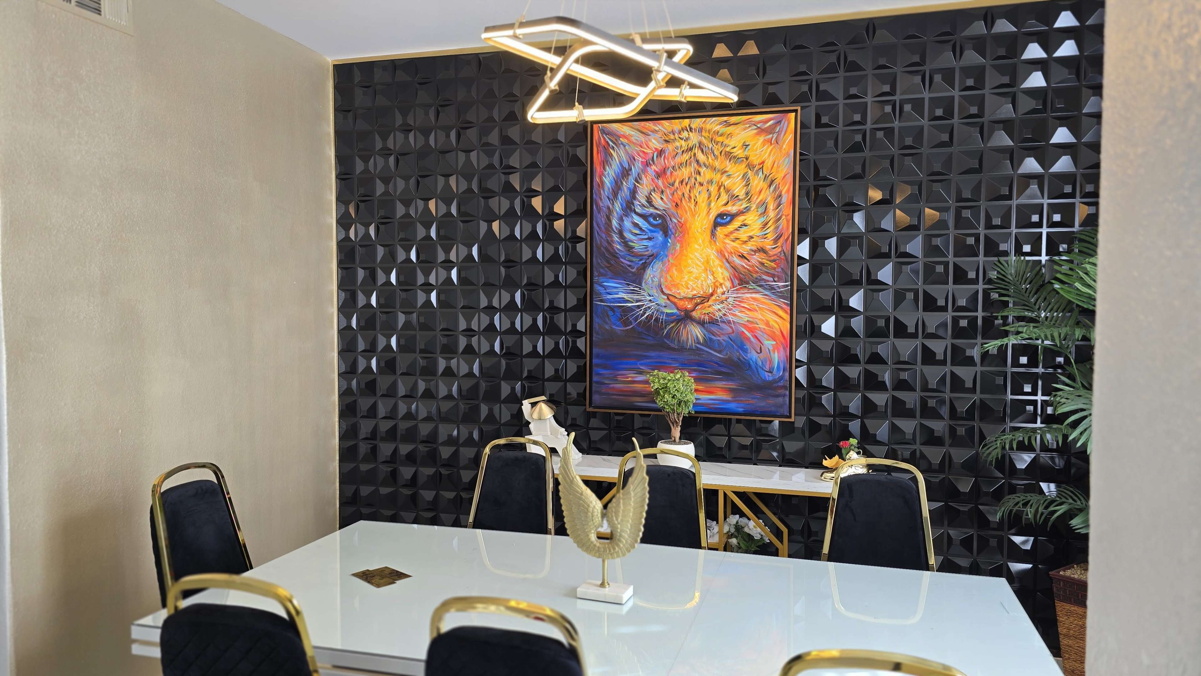The image shows a modern dining room with a white table surrounded by black chairs, featuring a colorful lion portrait on dark textured wall.