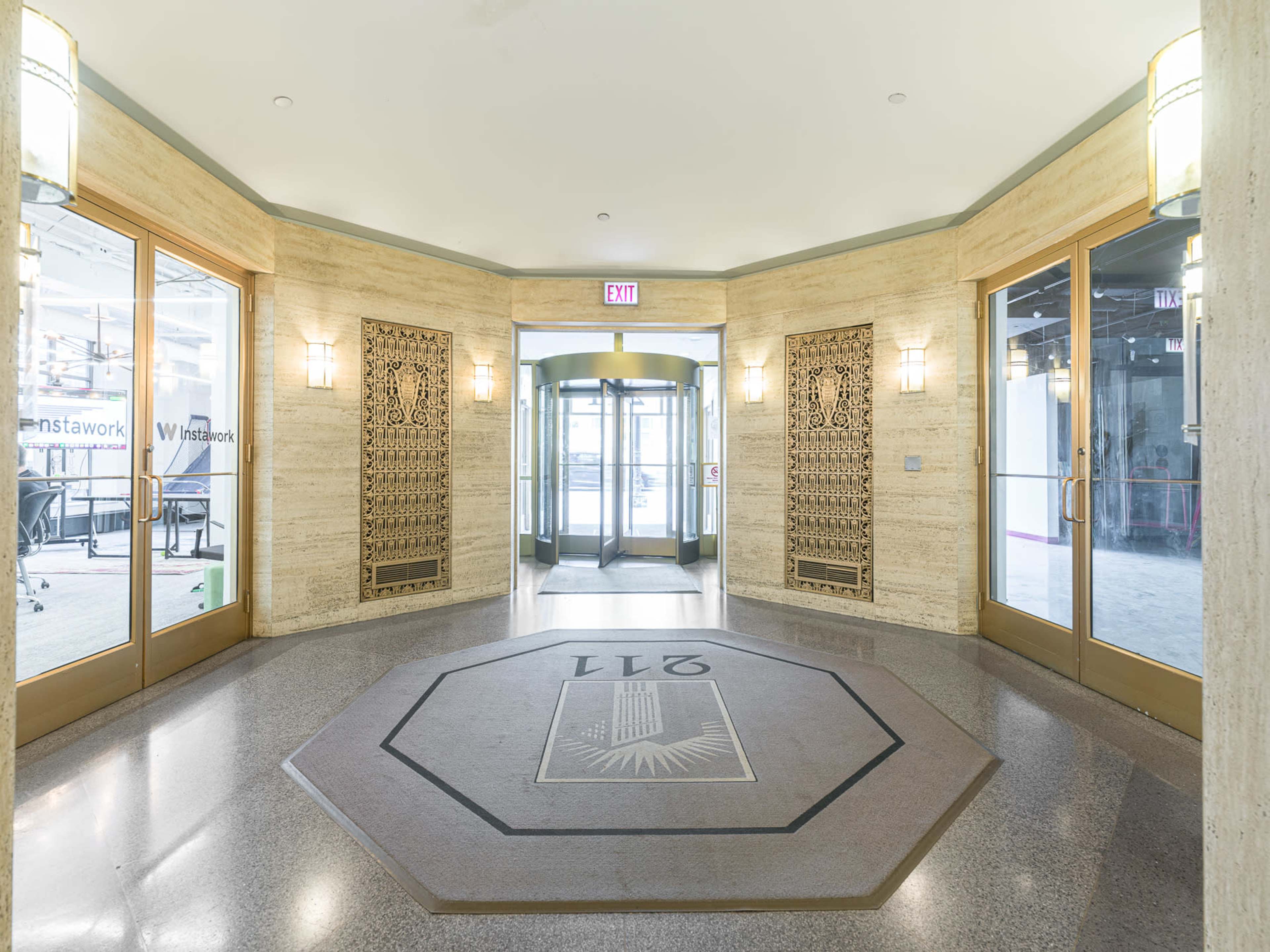 The image features a modern entrance area with a revolving glass door, decorative wall panels, and an octagonal floor design labeled "271."