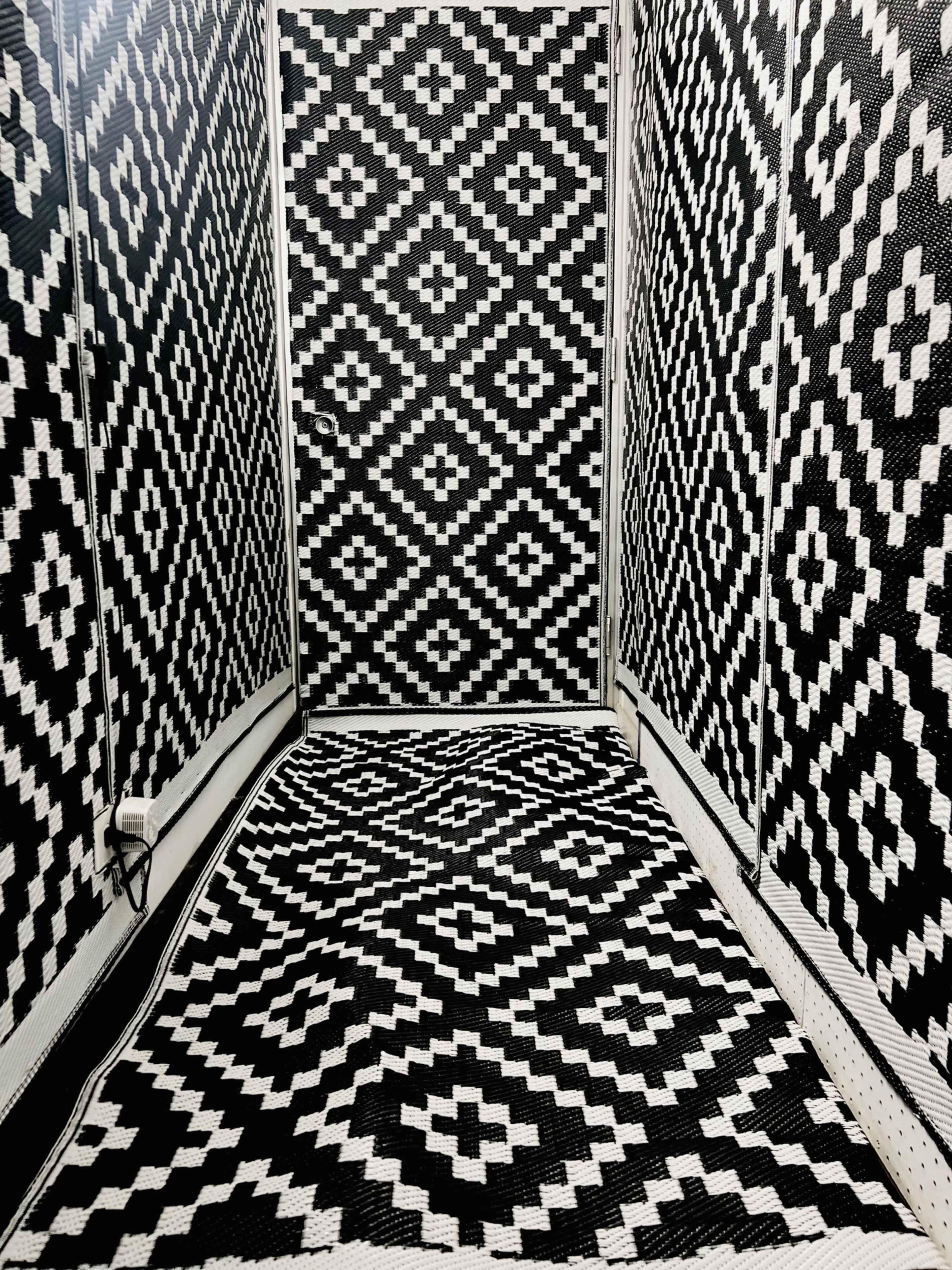 The image shows a room with walls and flooring covered in a geometric black and white pattern.
