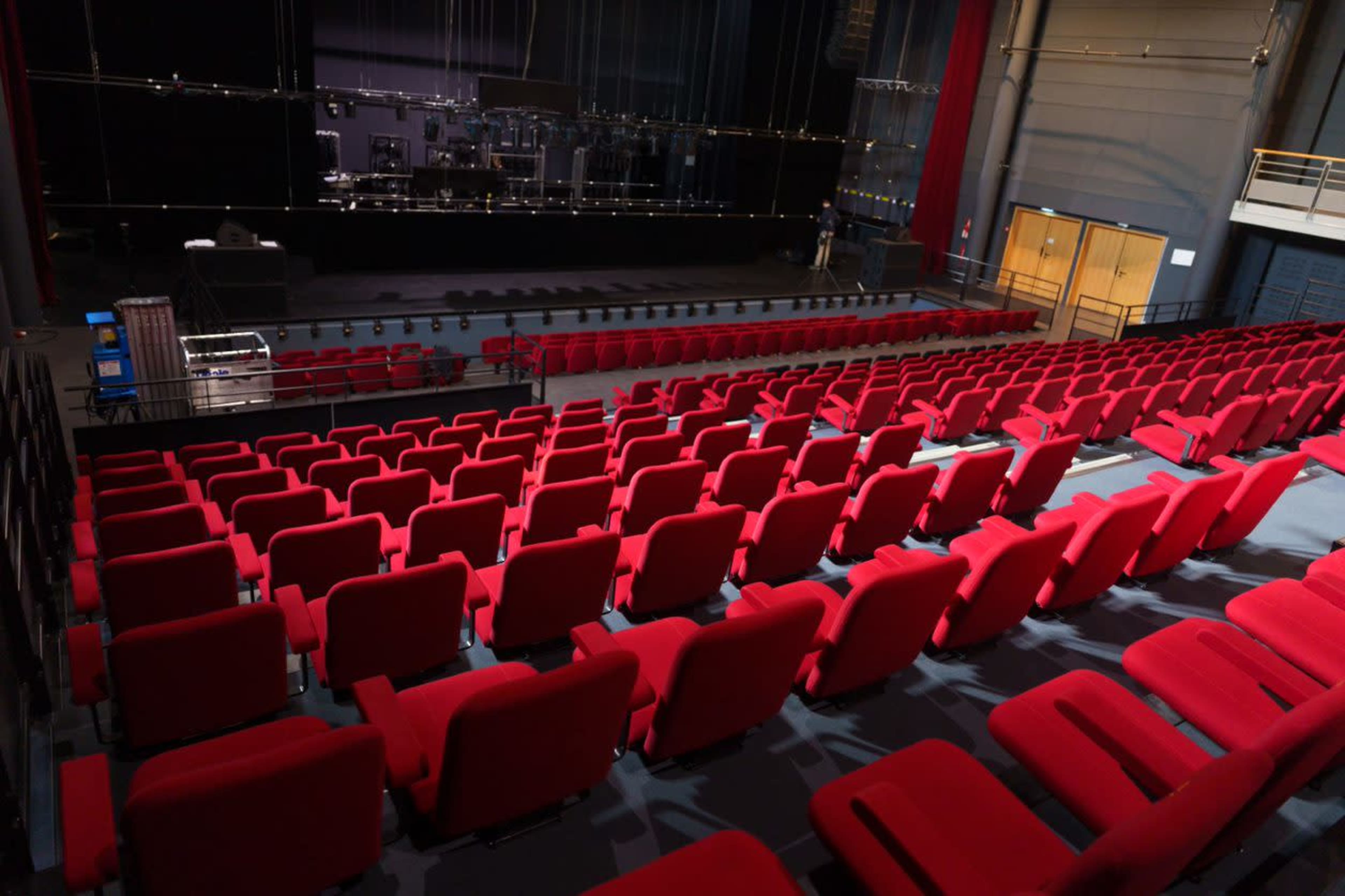 A stage and an audience area filled with red chairs in a theater setting.