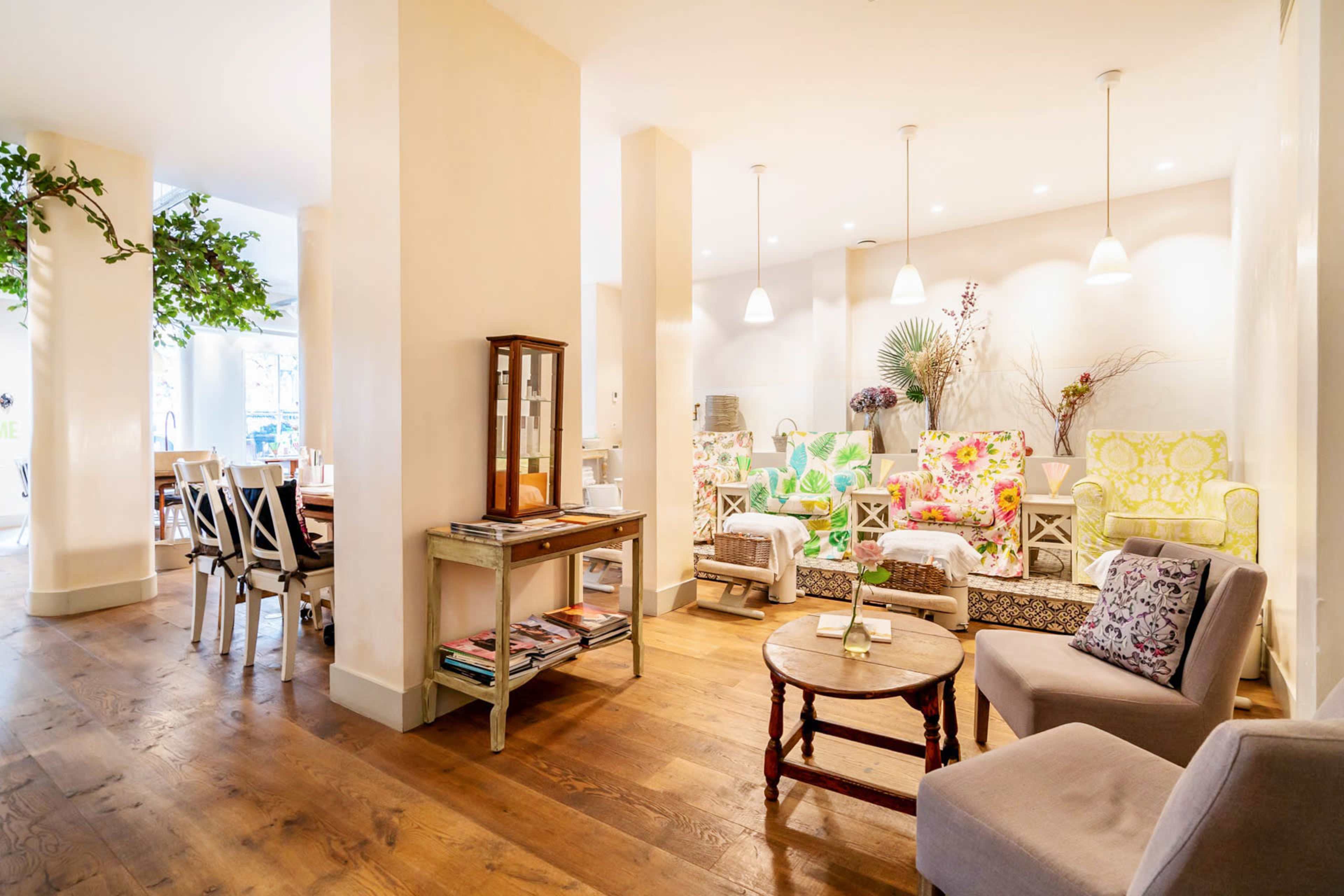 A bright and inviting café features colorful upholstered seating, light wooden floors, and a mix of tables and chairs arranged for dining.