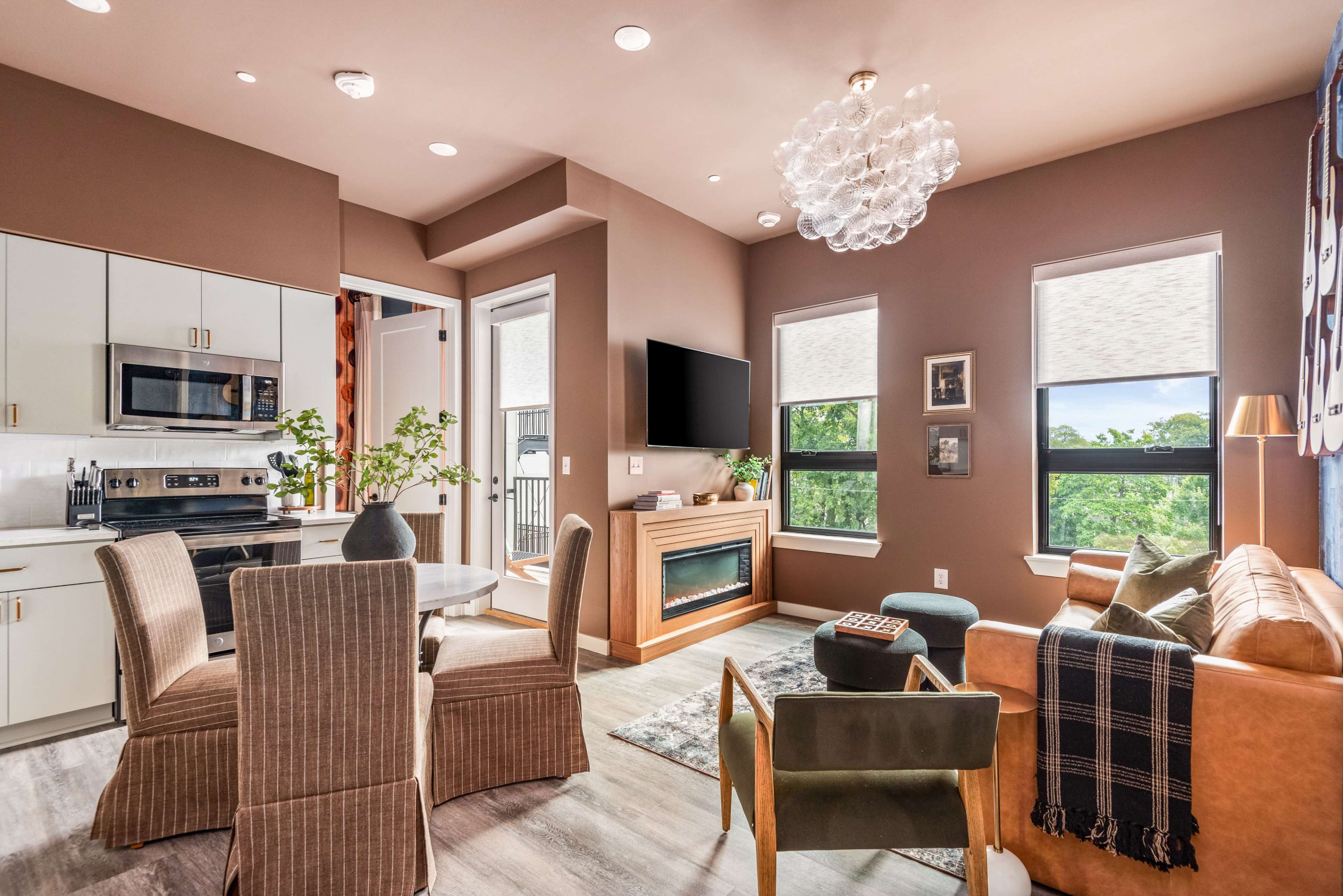 The image shows a modern living area with a kitchen, dining table, and seating area featuring a couch and decorative elements.