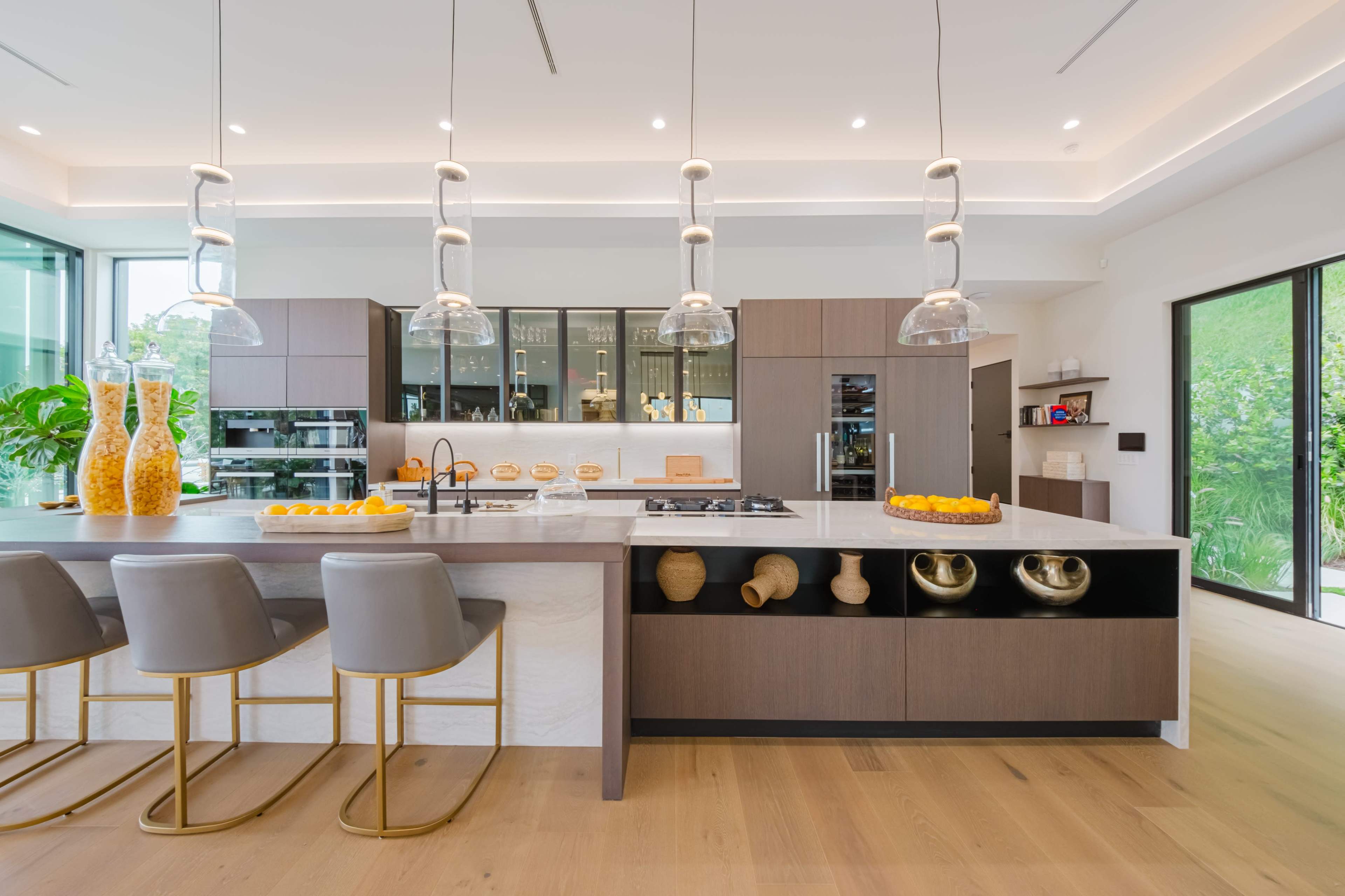 A modern kitchen featuring a large island with bar seating, pendant lights, and sleek cabinetry.