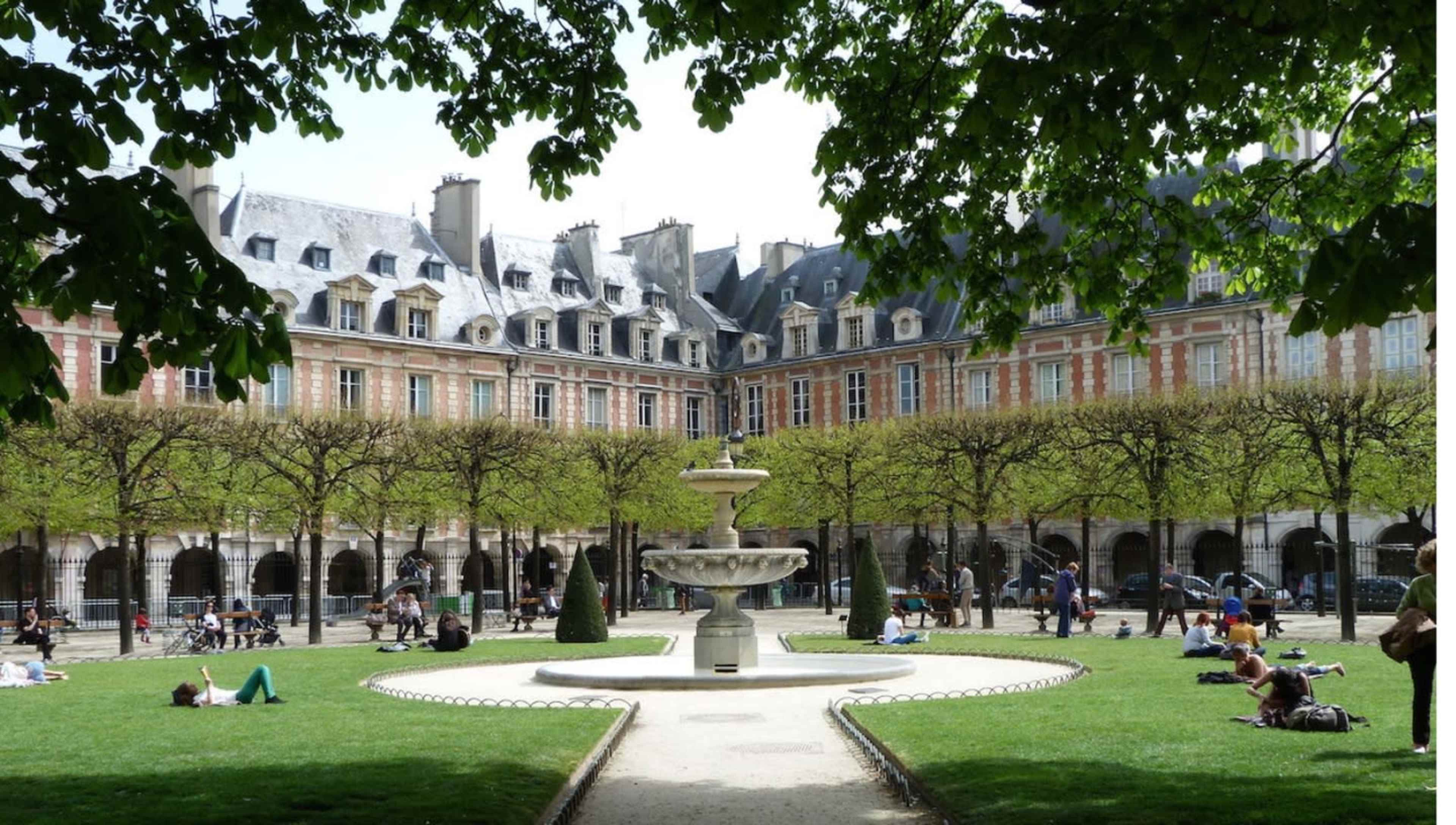The image shows a landscaped garden in a Parisian square, featuring a central fountain surrounded by manicured grass and people lounging on the lawn.
