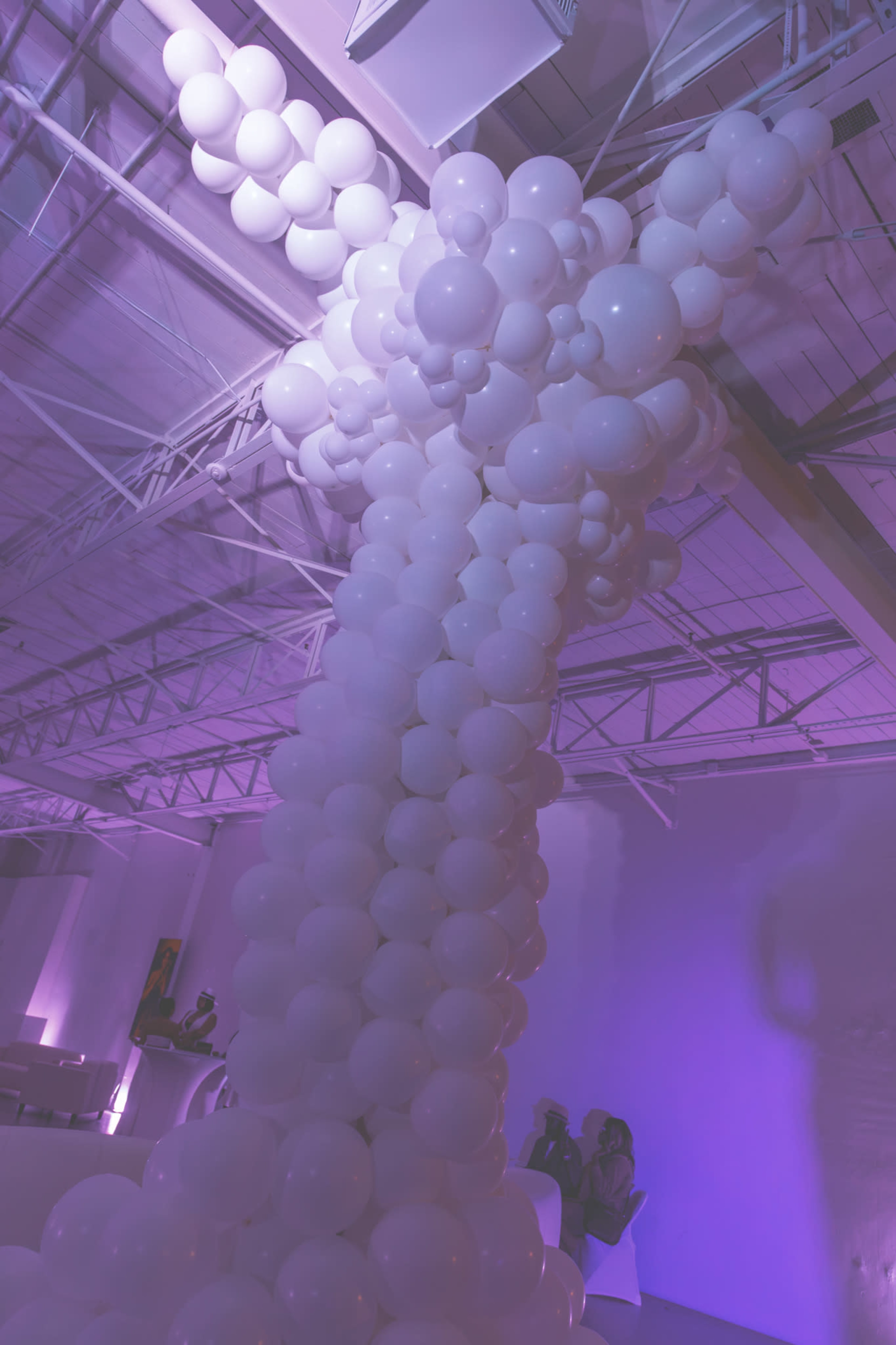 A tall column made of white balloons is arranged in a stylish formation against a softly lit background.