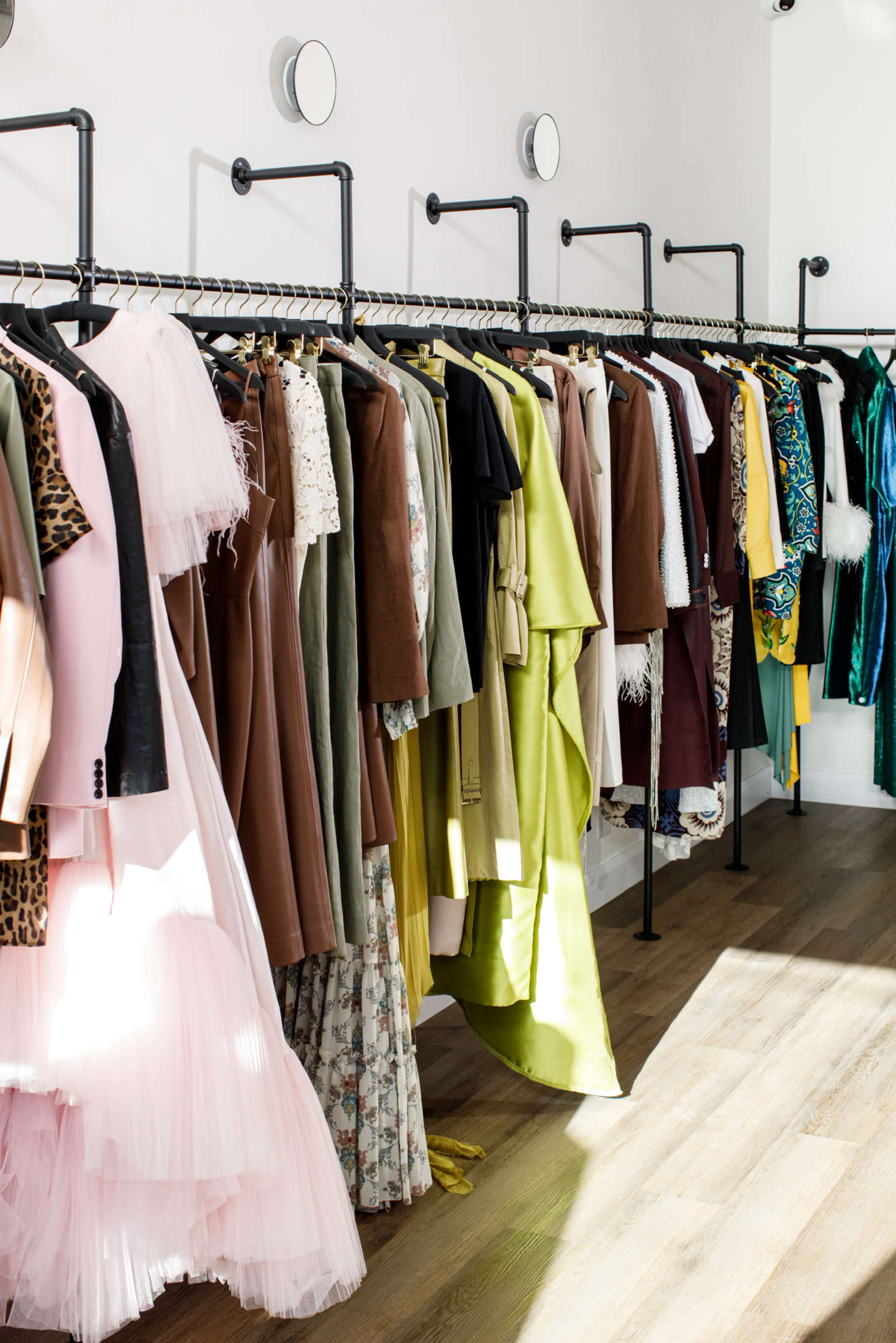 The image shows a clothing rack displaying a variety of dresses and garments in different colors and styles.