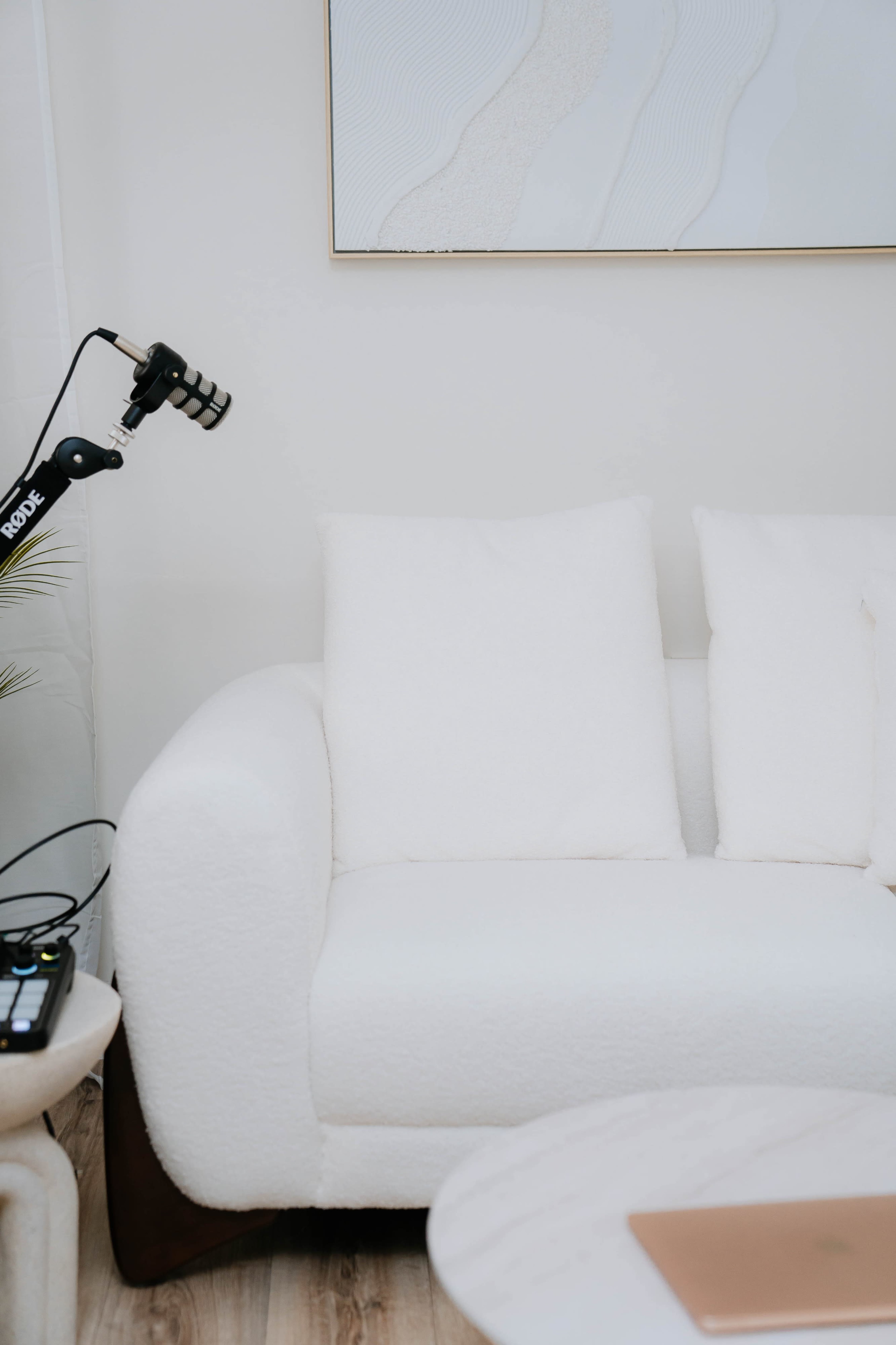 The image features a white sofa with three cushions beside a microphone on a stand and a small table.