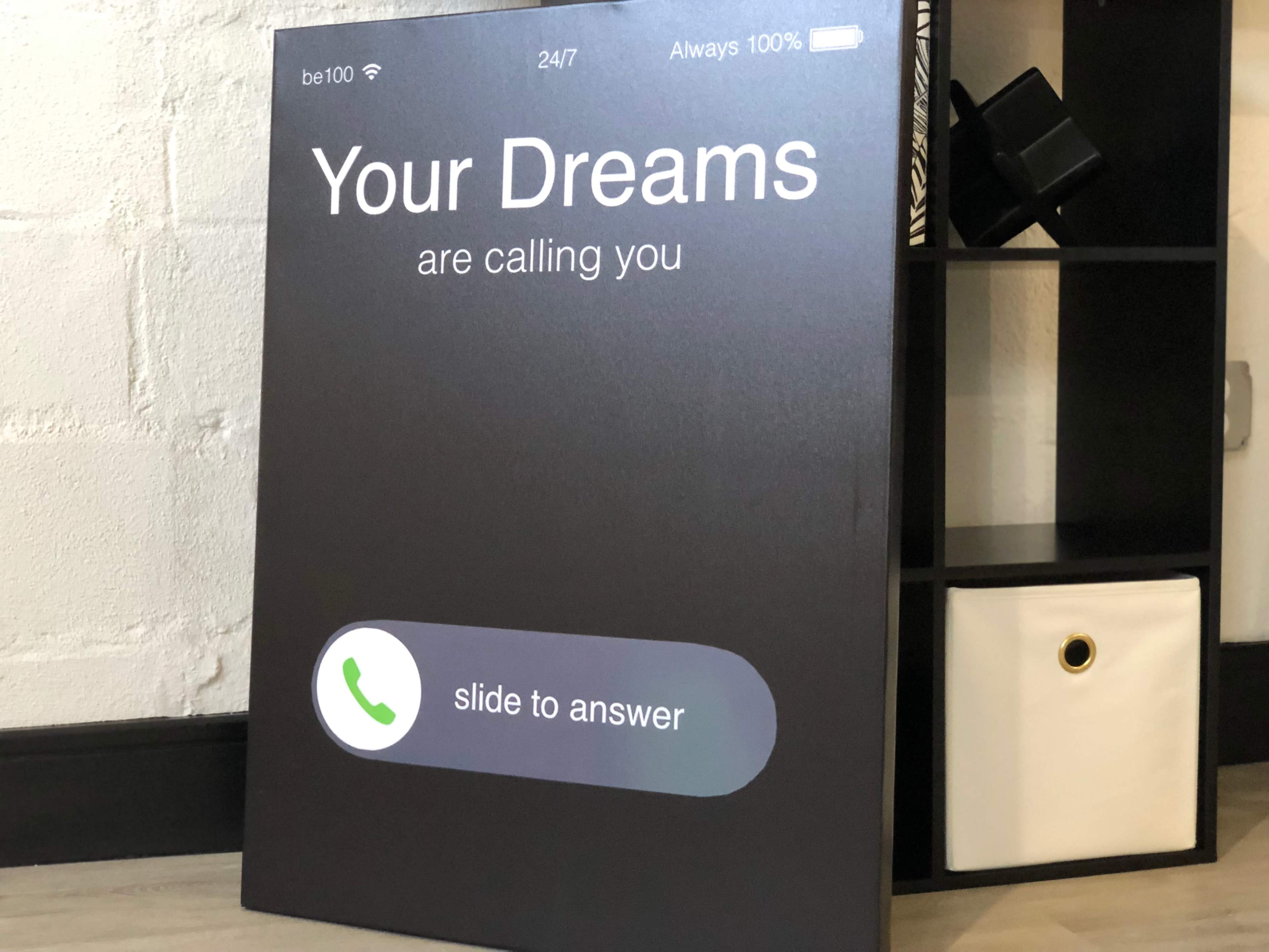 A large display resembling a smartphone screen with the message "Your Dreams are calling you" and a prompt to "slide to answer" on a dark background.