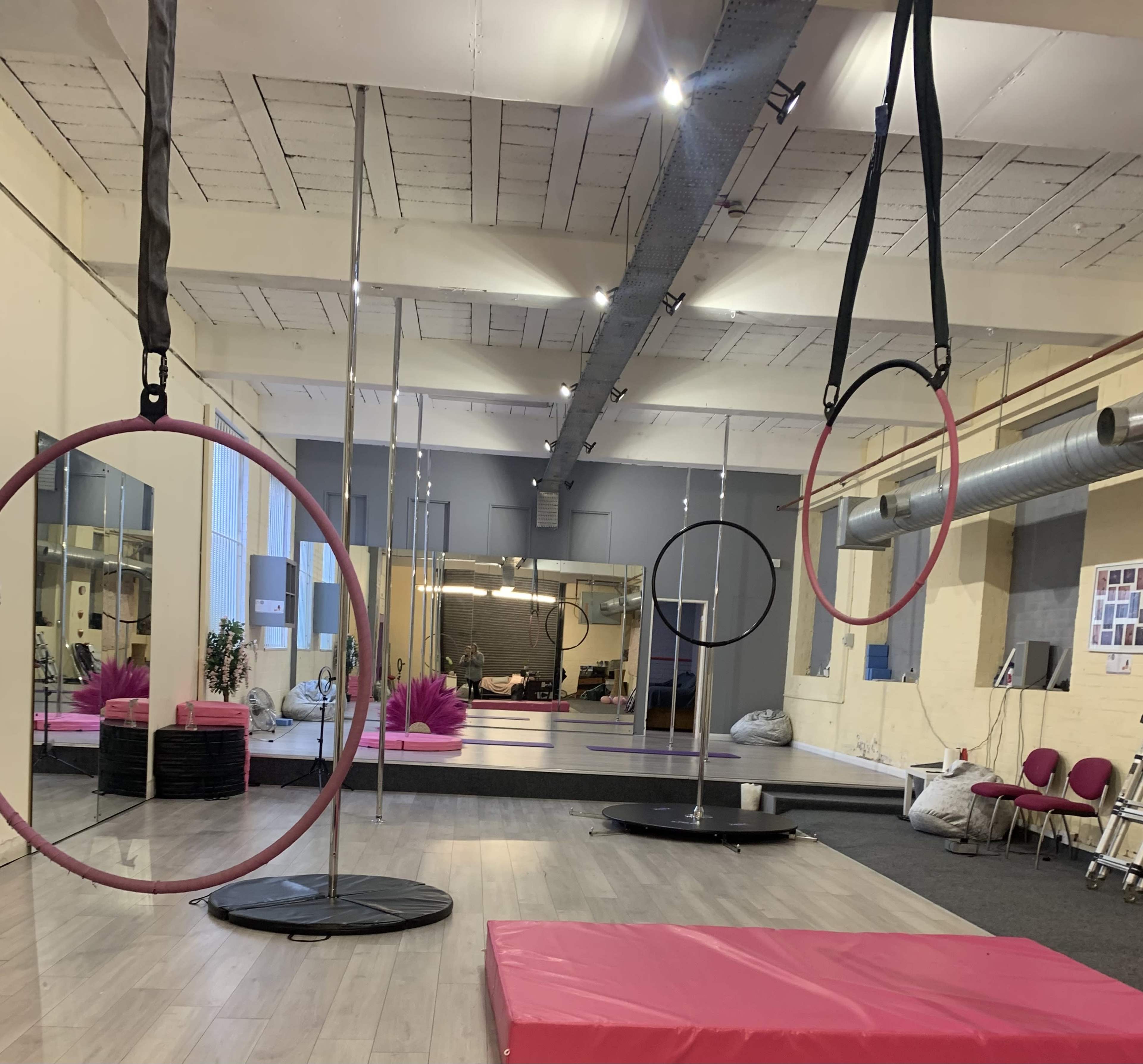 An aerial fitness studio with several suspended hoops, mirrors, and soft flooring.
