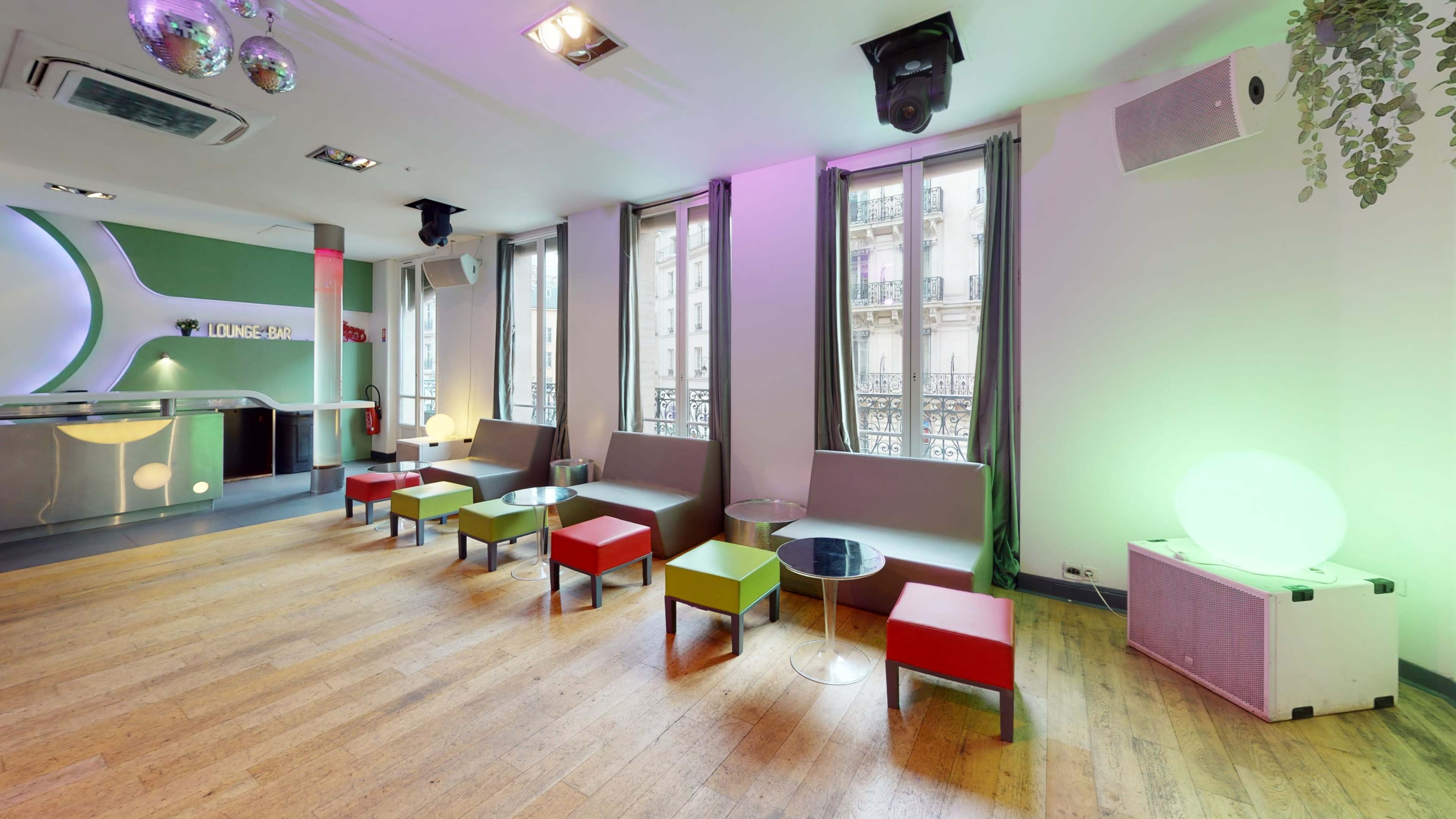 A modern lounge area with low seating, colorful side tables, and large windows letting in natural light.