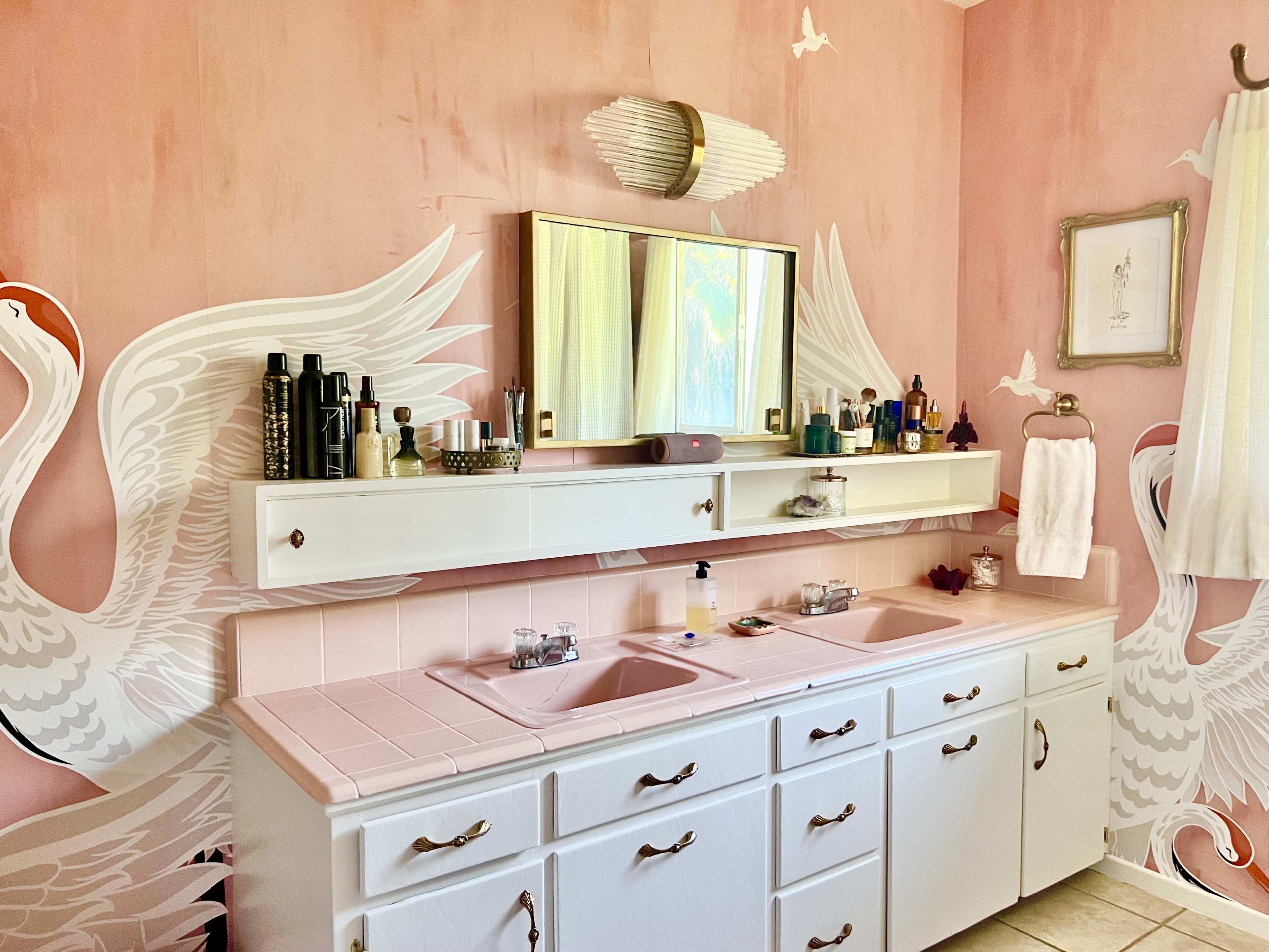 The bathroom features a double vanity with a large mirror above and pink walls decorated with white swan murals.