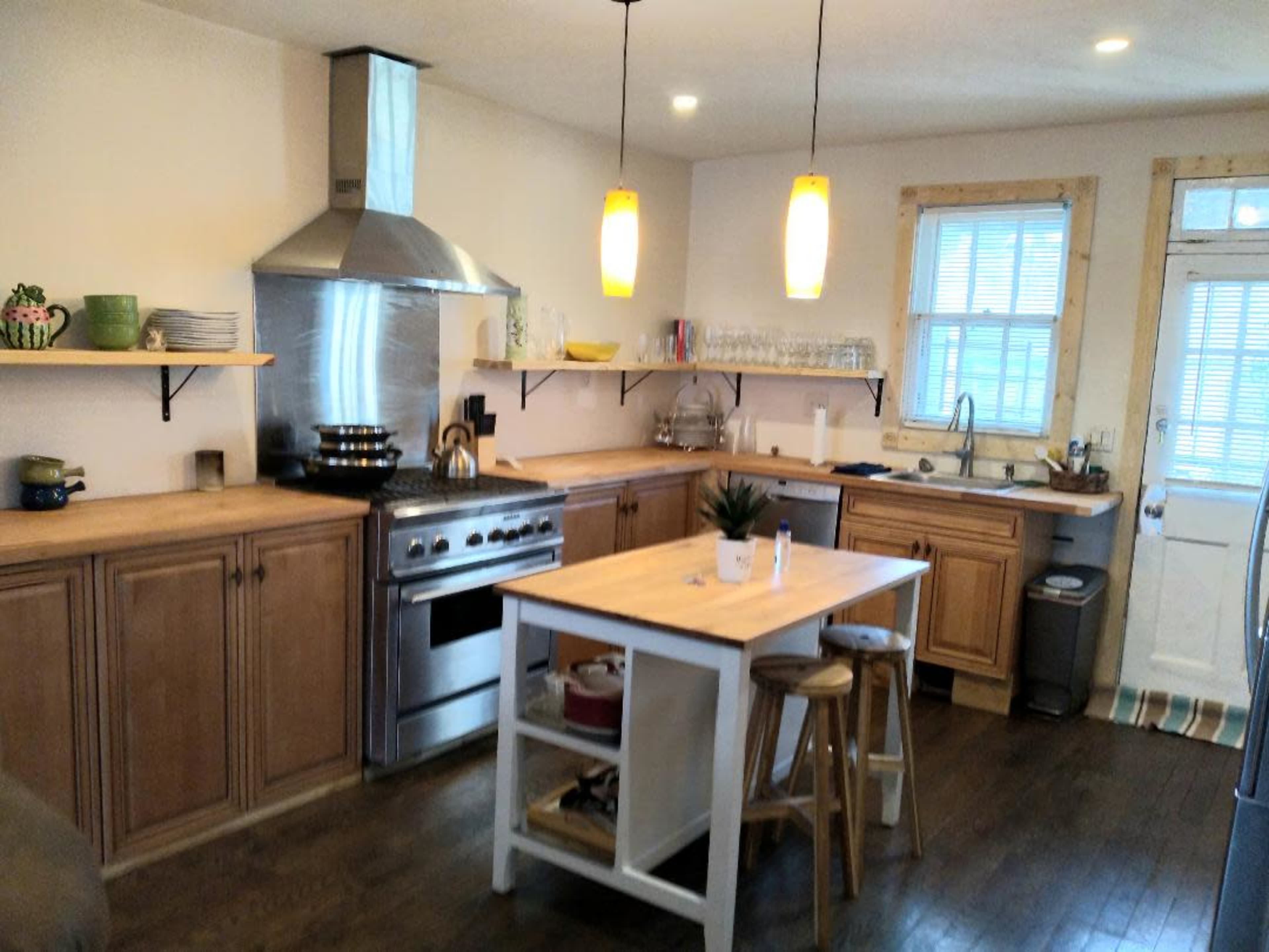 A modern kitchen with wooden cabinets, a stainless steel stove, and an island with stools.