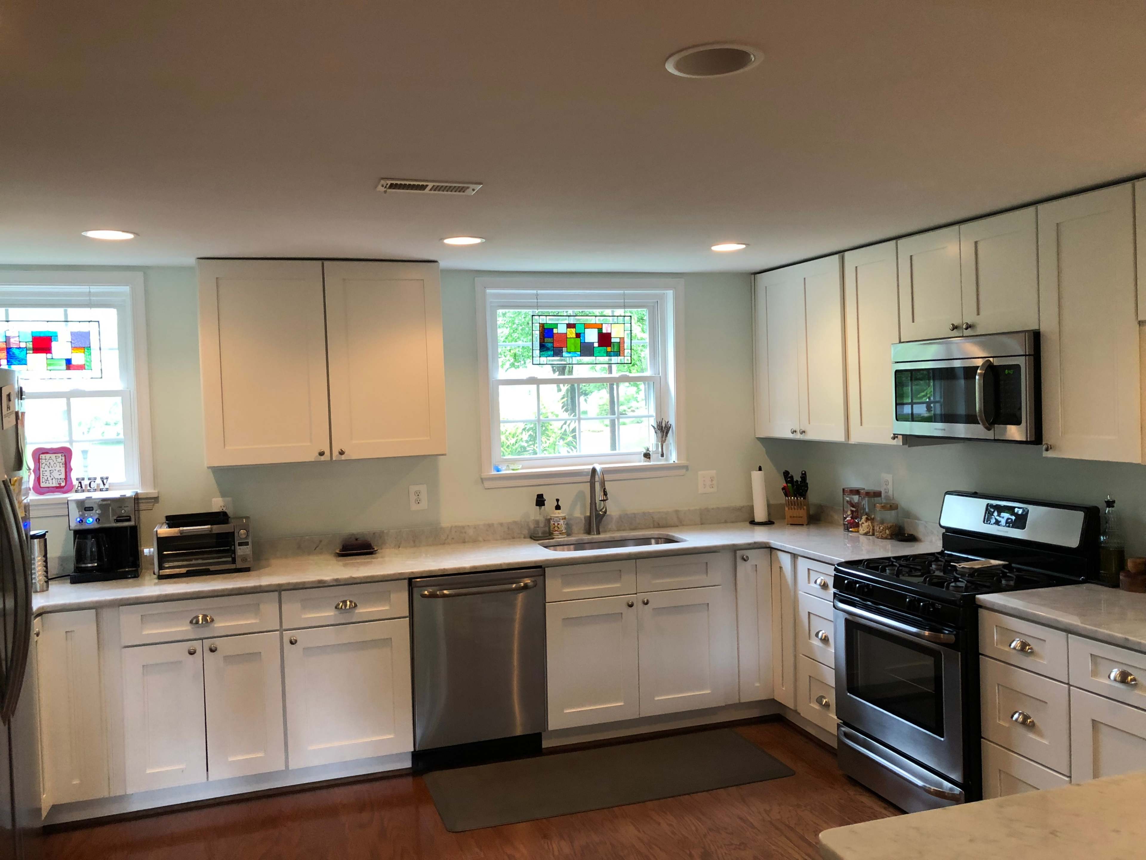 The kitchen features white cabinets, stainless steel appliances, a marble countertop, and stained glass windows.