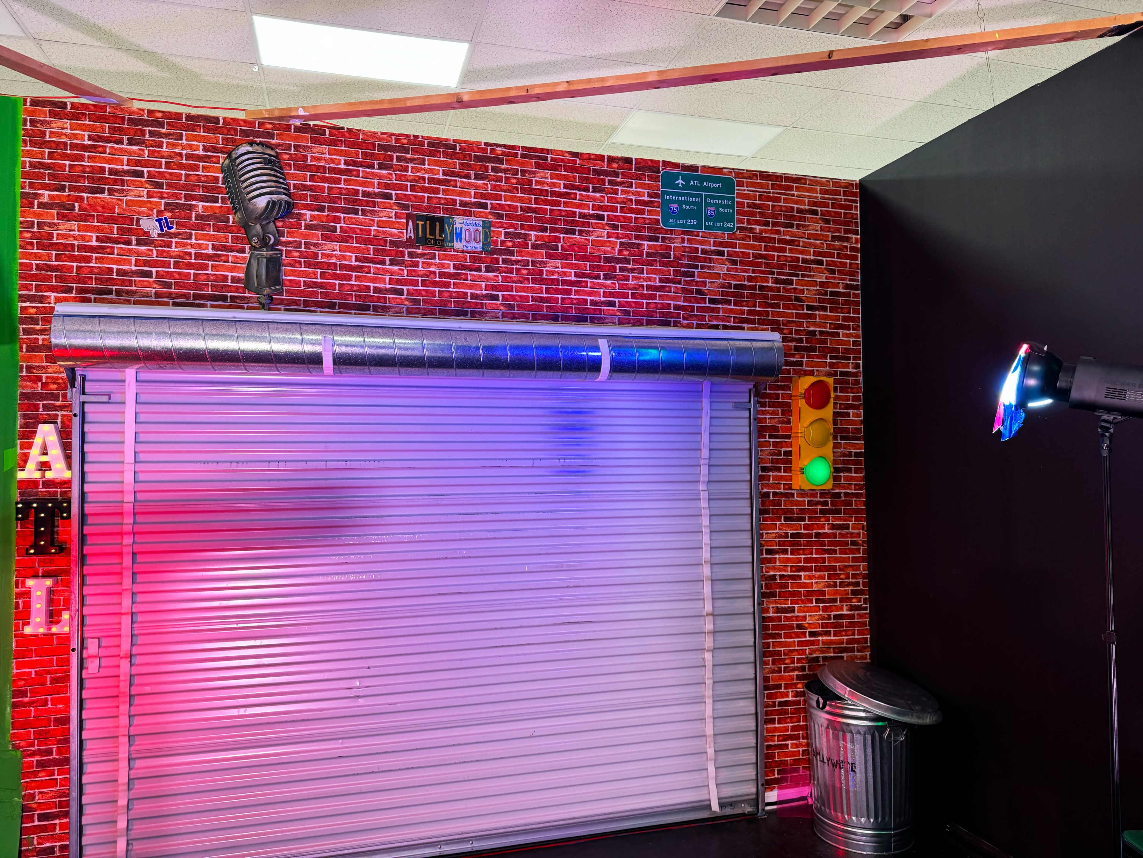 The scene features a brick wall backdrop with a vintage microphone and a rolled-down metal shutter, illuminated by colorful lights.