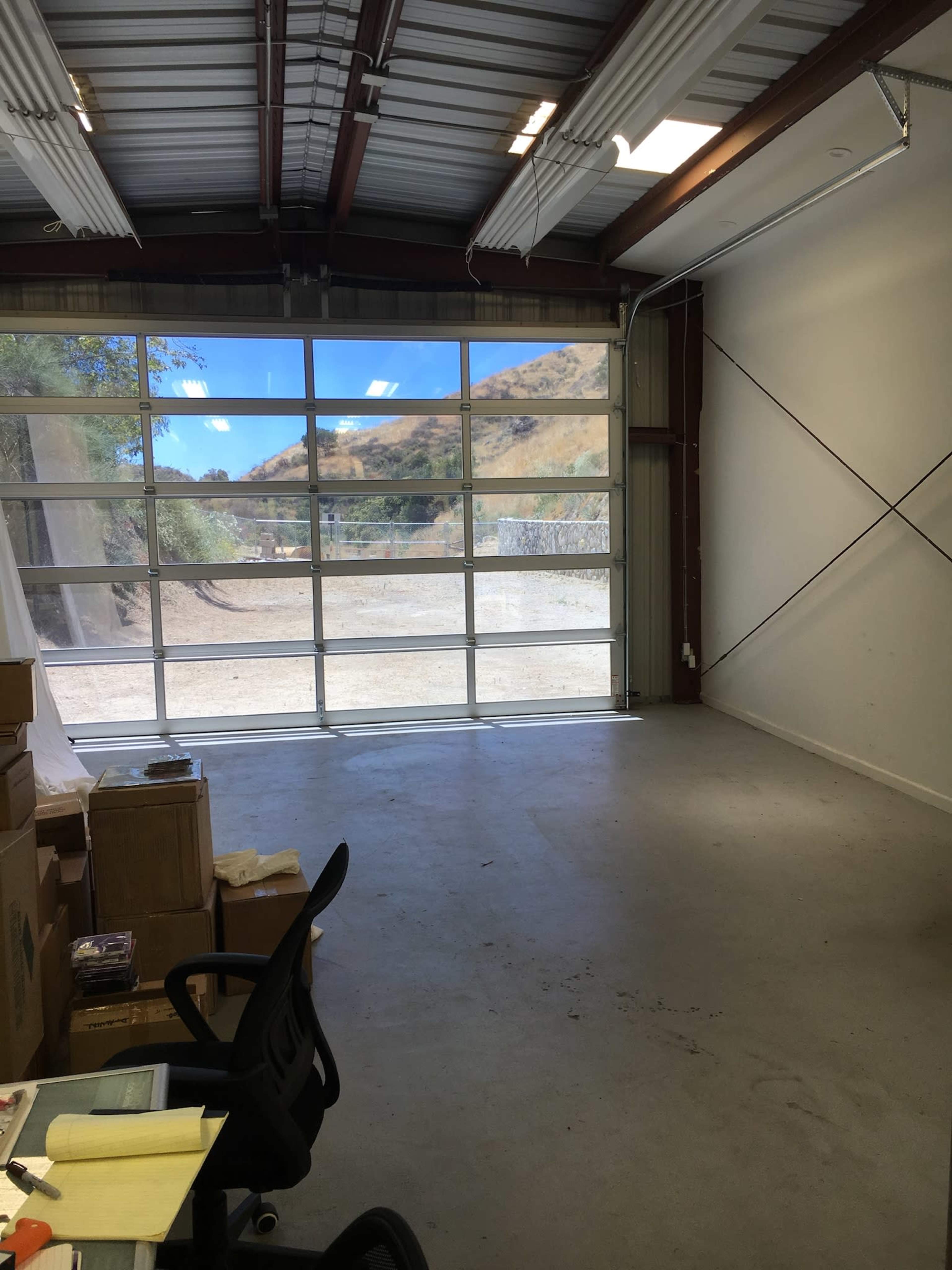 An empty garage or storage space with large glass doors and boxes stacked on the floor.