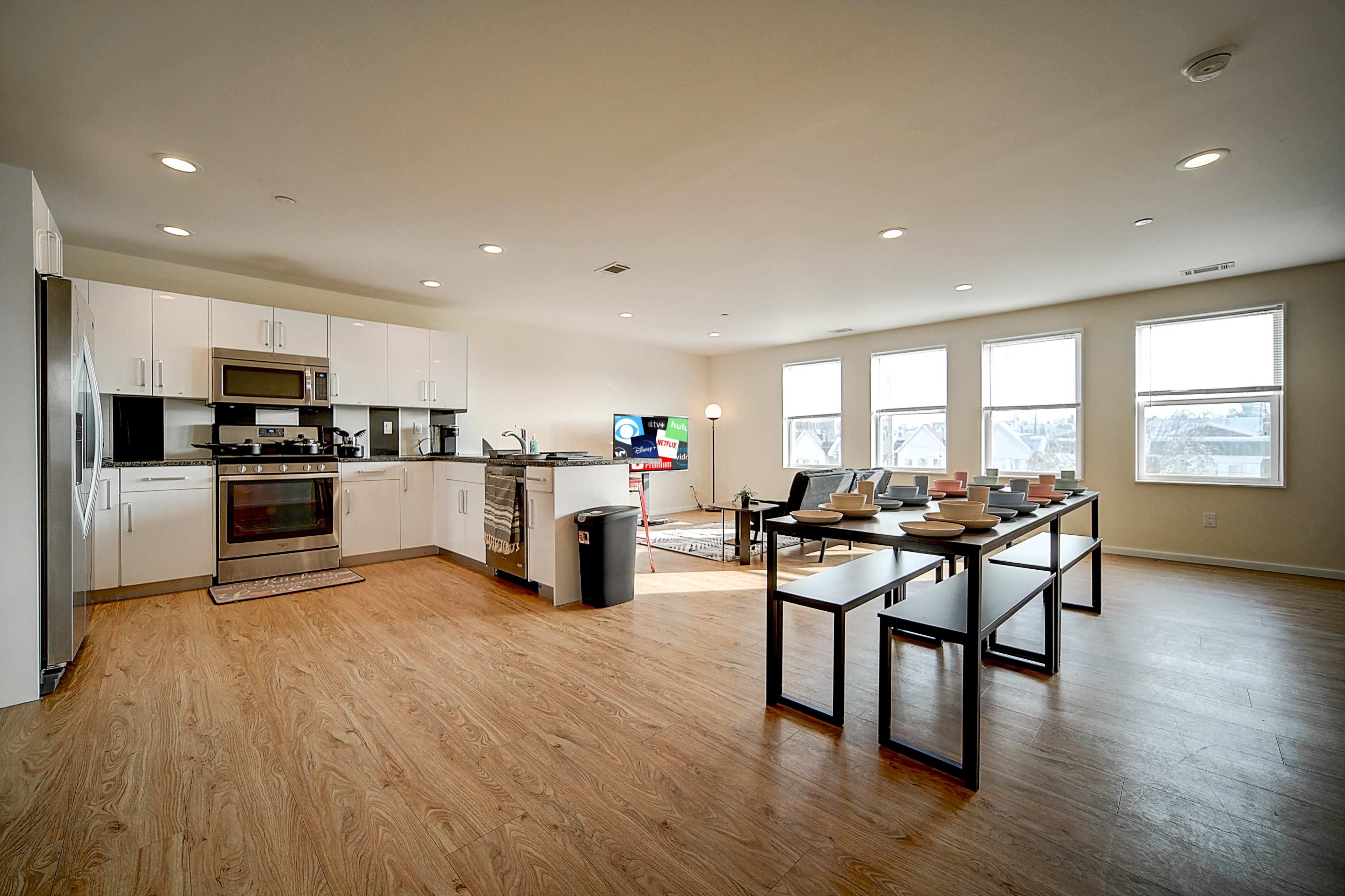 A modern, open-concept kitchen and living area with a dining table and large windows allowing natural light.
