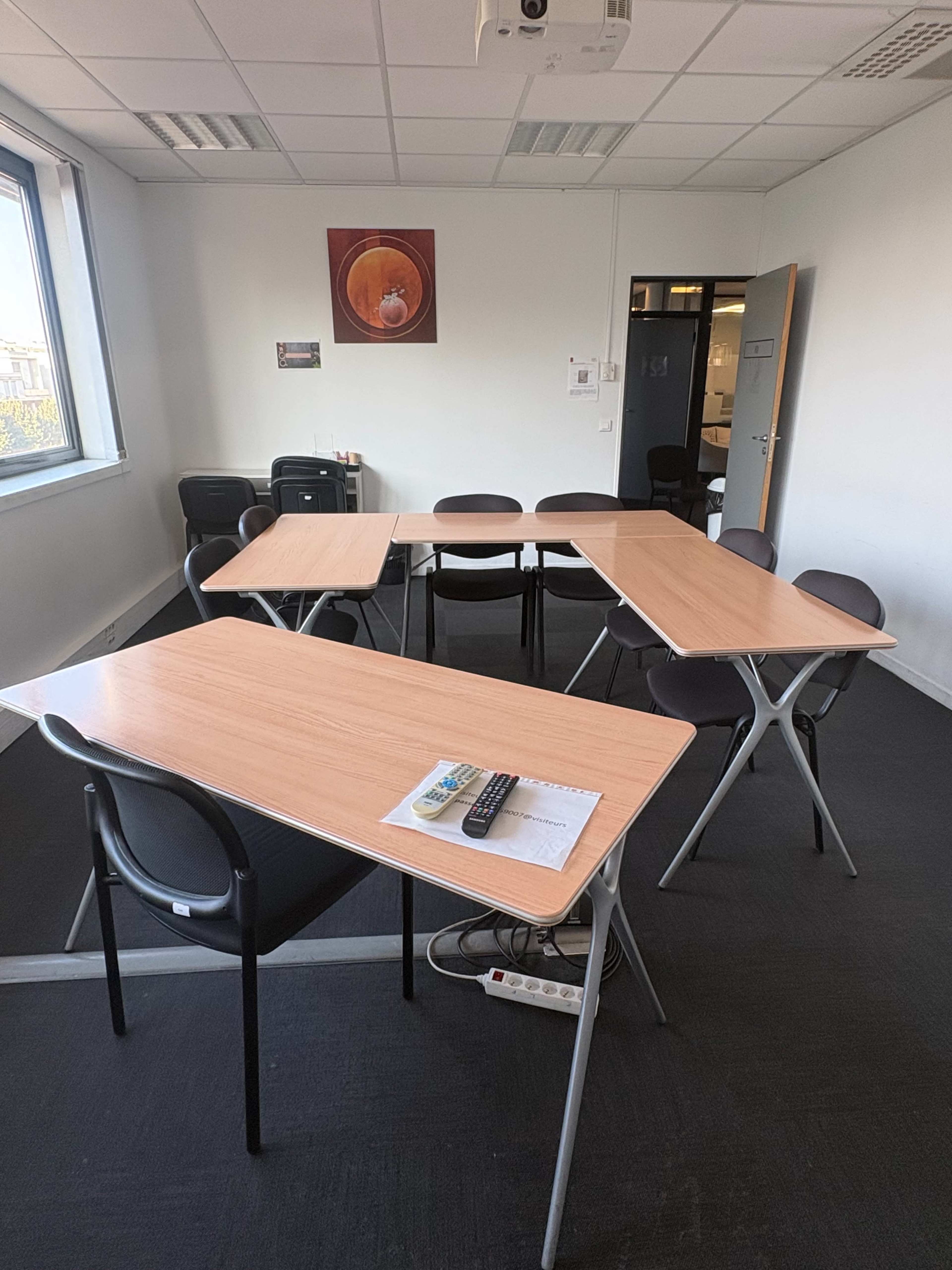 The image shows a meeting room with several folding tables arranged in a cluster and black chairs placed around them.