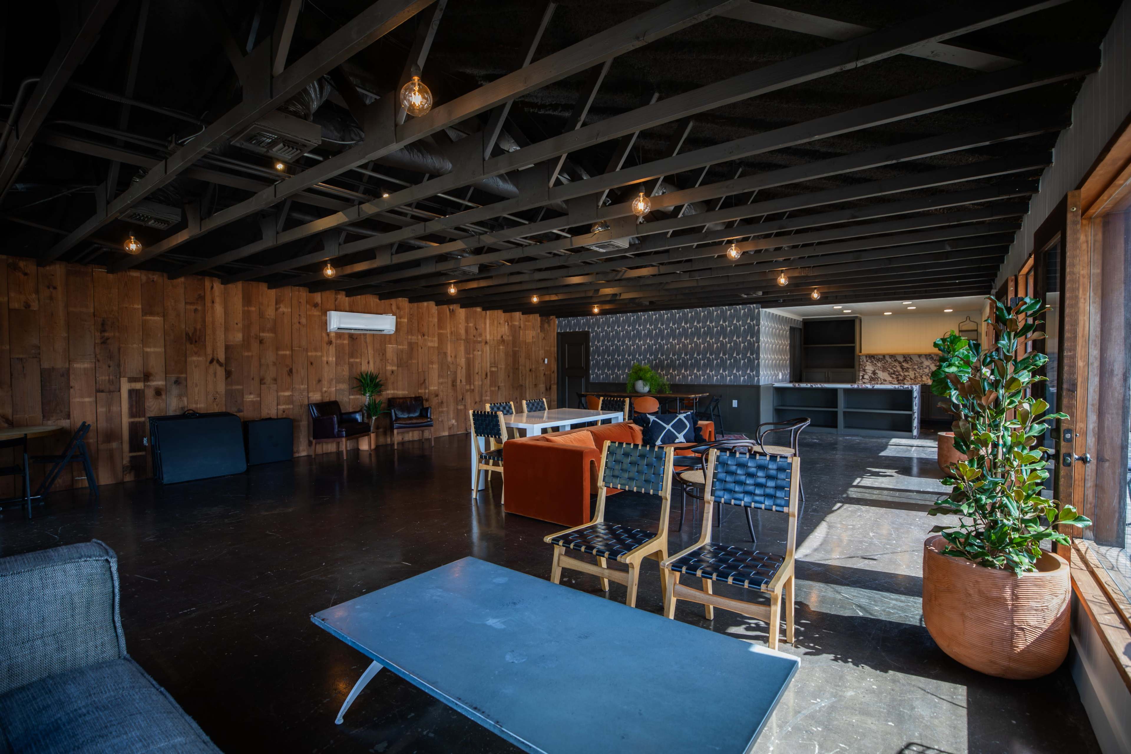 The interior features an open space with wooden walls, modern furniture, and a sleek bar area.
