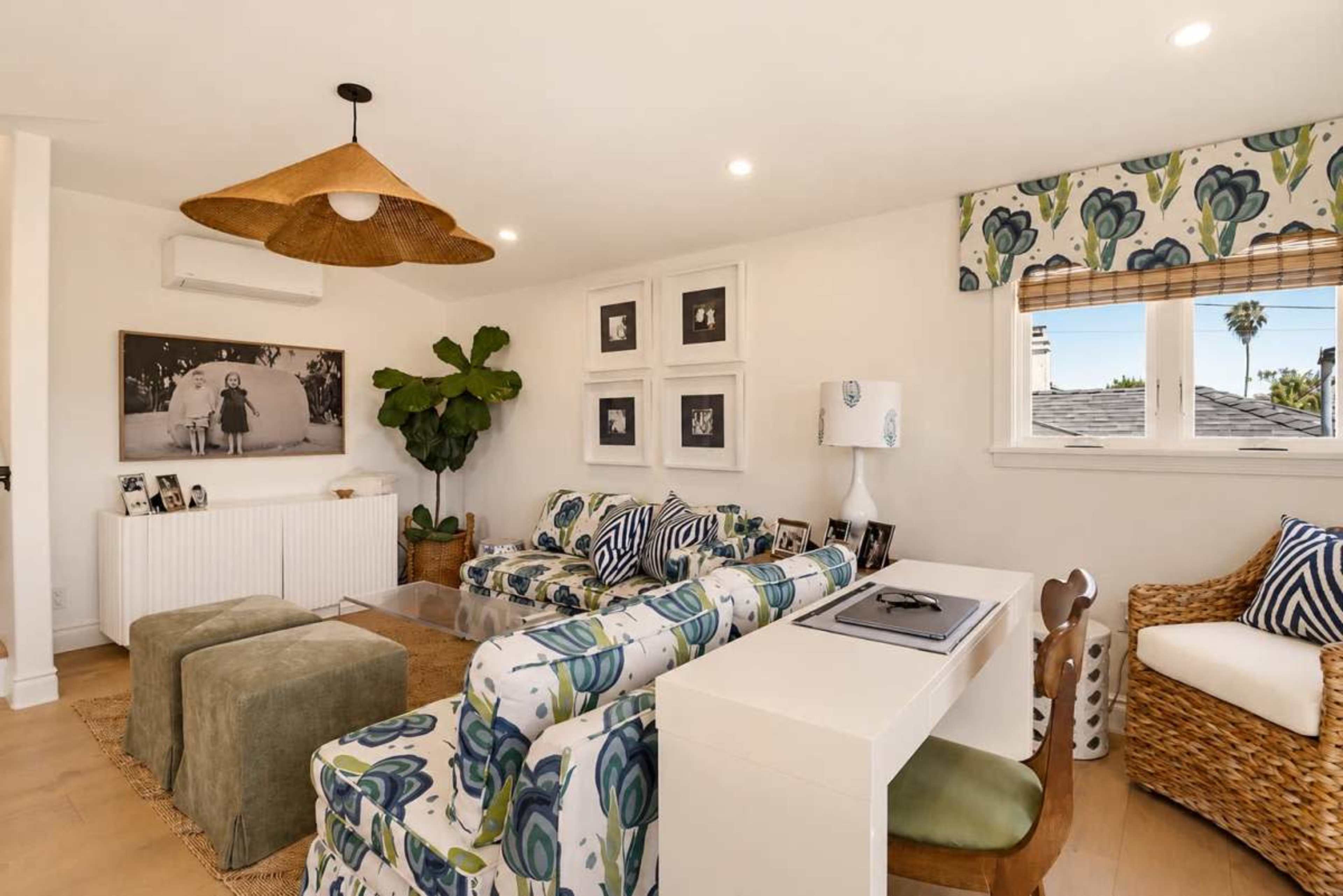 The living room features patterned sofas, a white console table, and a large plant under a woven pendant light.