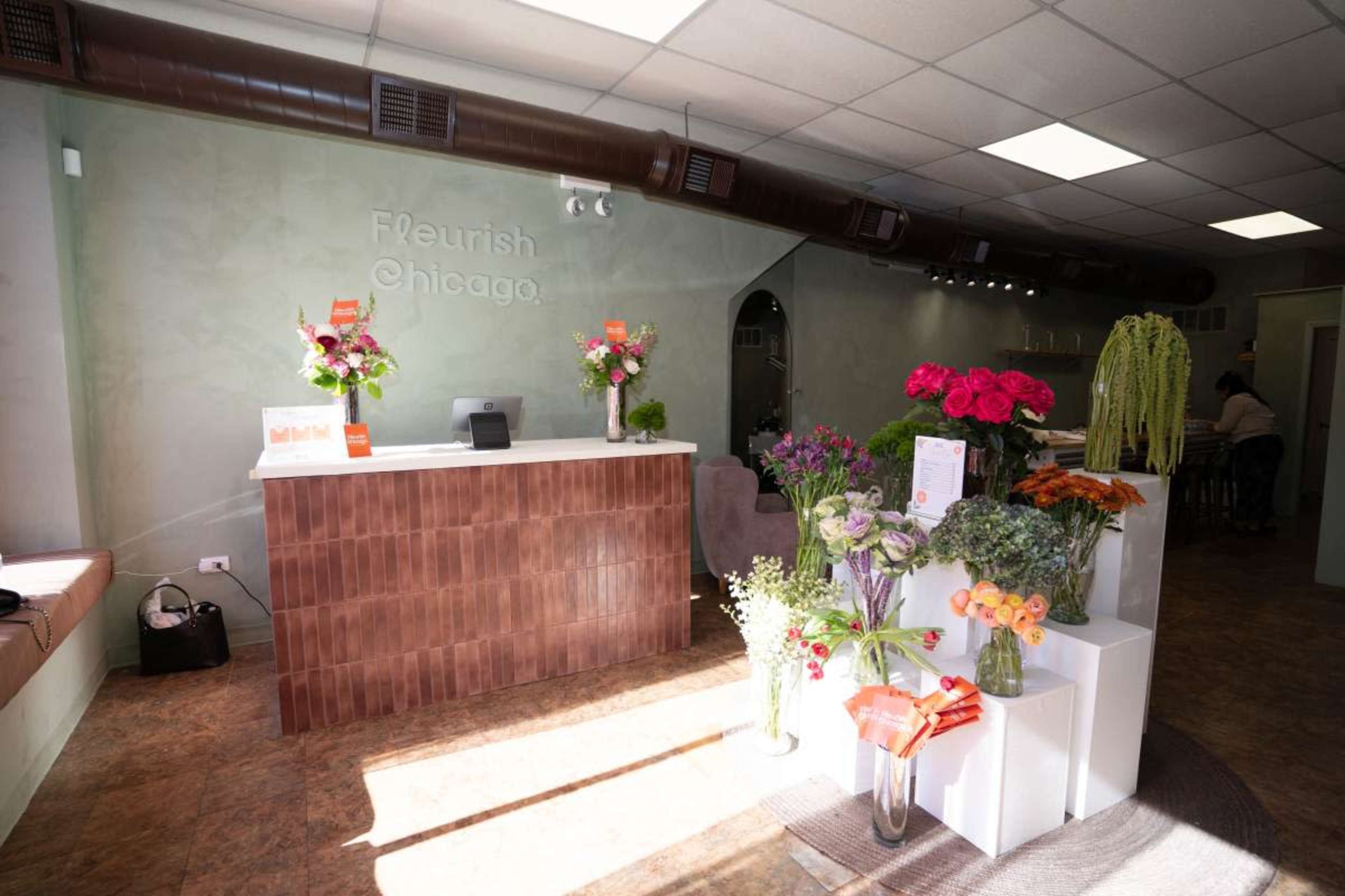 The image shows a flower shop interior with a reception counter, various flower arrangements, and a minimalist, modern design.